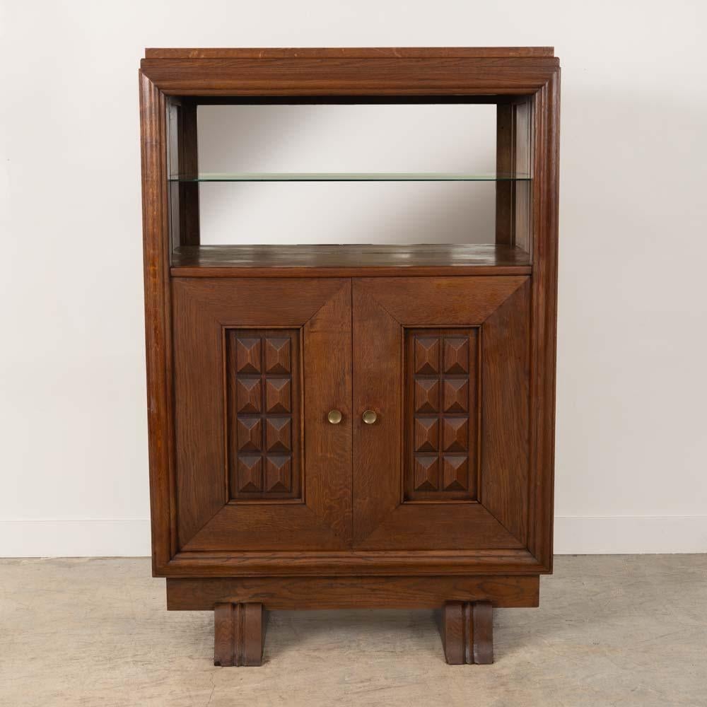 Incroyable meuble de bar en bois sculpté de Charles Dudouyt, France, années 1940. Magnifiques détails géométriques sculptés sur deux portes d'entrée. Niveau supérieur ouvert avec étagère en verre et dos en miroir. Le meuble repose sur deux pieds