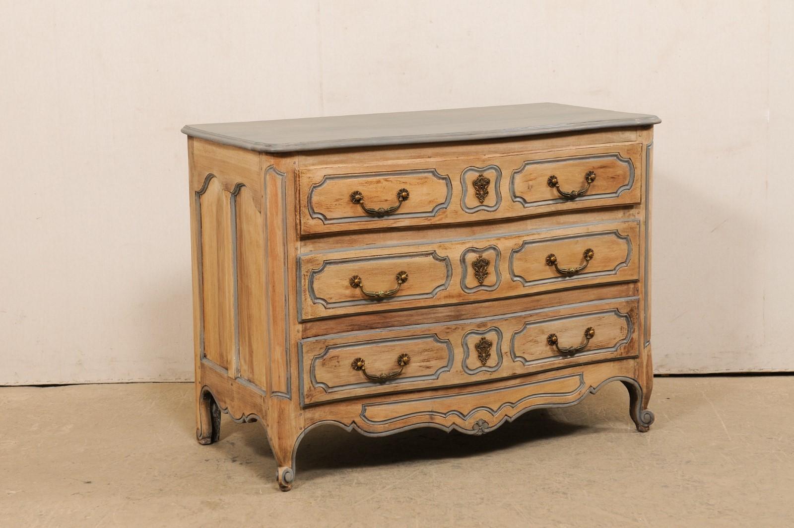 Commode à trois tiroirs en bois sculpté et blanchi. Cette commode vintage de France présente un plateau rectangulaire aux angles arrondis, surmontant un corps qui abrite trois tiroirs pleins, flanqués de montants latéraux ronds, avec une jupe