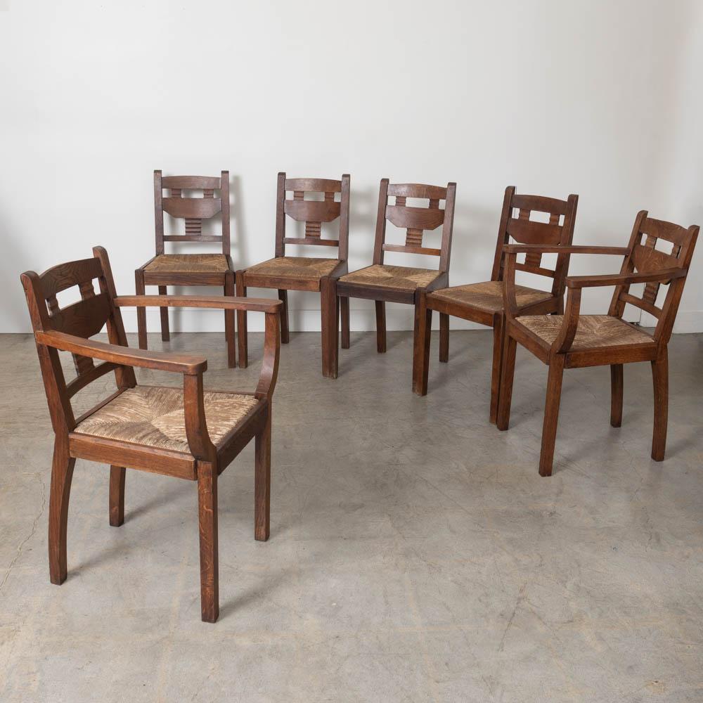 Great set of six wood and woven chairs by Charles Dudouyt from France, 1940s. Carved legs with beautiful carved wood design on backs. Two chairs with carved wood arms. Original woven rush seats in great vintage condition. Original dark wood finish