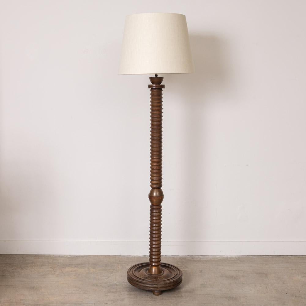 Wonderful vintage carved wood floor lamp from France, 1940s. Large carved wood stem with brass detail on circular base. Original finish shows nice age and patina. Newly re-wired with brass socket and new large linen shade with diffuser. Truly a