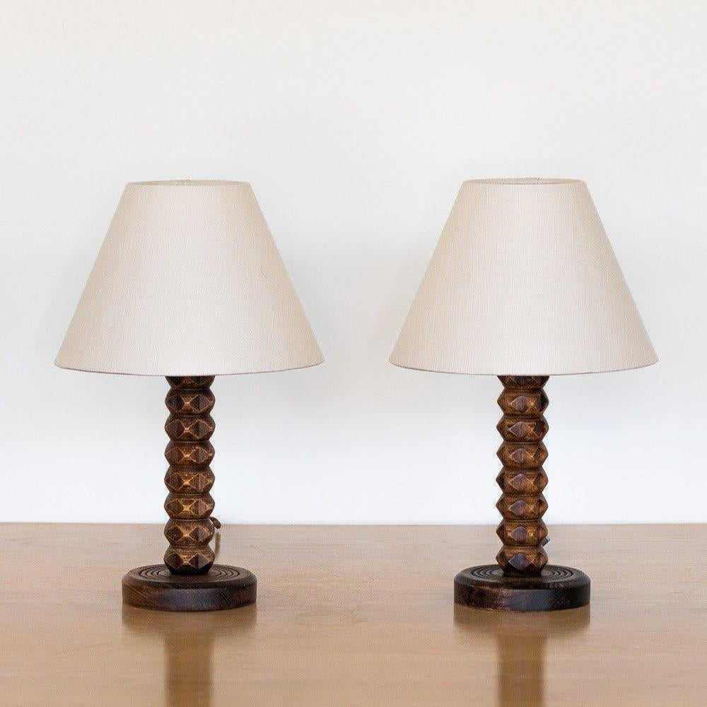 Great carved wood table lamp from France, 1940s by Charles Dudouyt. Beautiful carved chevron design with original dark wood finish. New linen shade and newly re-wired. Two available. Sold individually. Original wood finish has normal wear and patina.
