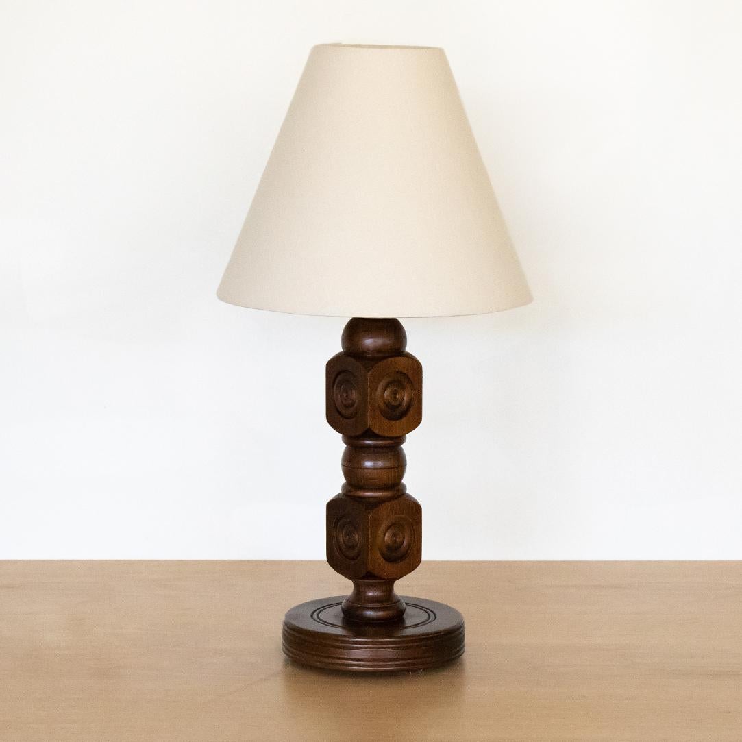 Handsome carved wood table lamp from France, 1940's in the style of Charles Dudouyt. Carved rectangle block and ball design with original wood finish. New oyster linen shade and newly re-wired. 

 