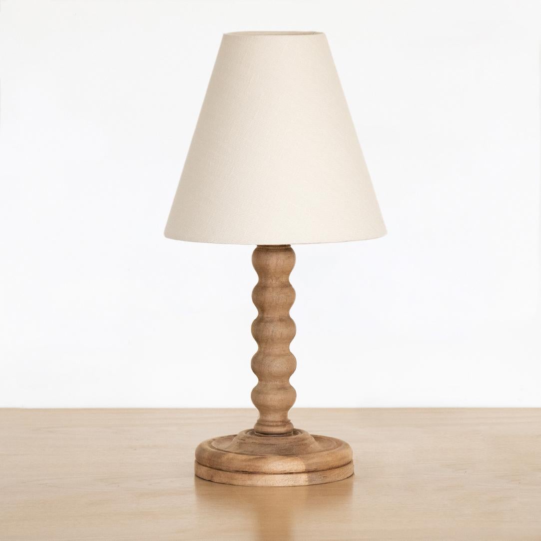 Beautiful carved wood table lamp from France, 1940s. Carved wavy stem with original light wood finish. New creamy linen shade and newly re-wired. 

Measures: Shade diameter 9.25
