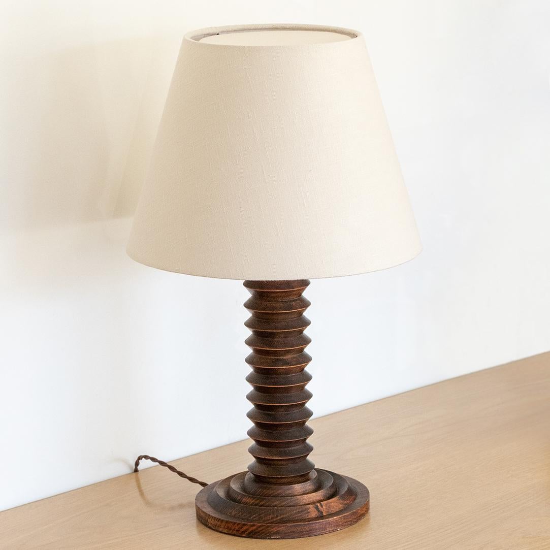 Hand carved wood table lamp from France, 1940's in the style of Charles Dudouyt. Carved wood stem with original wood finish. New linen shade with top diffuser and newly re-wired. 

