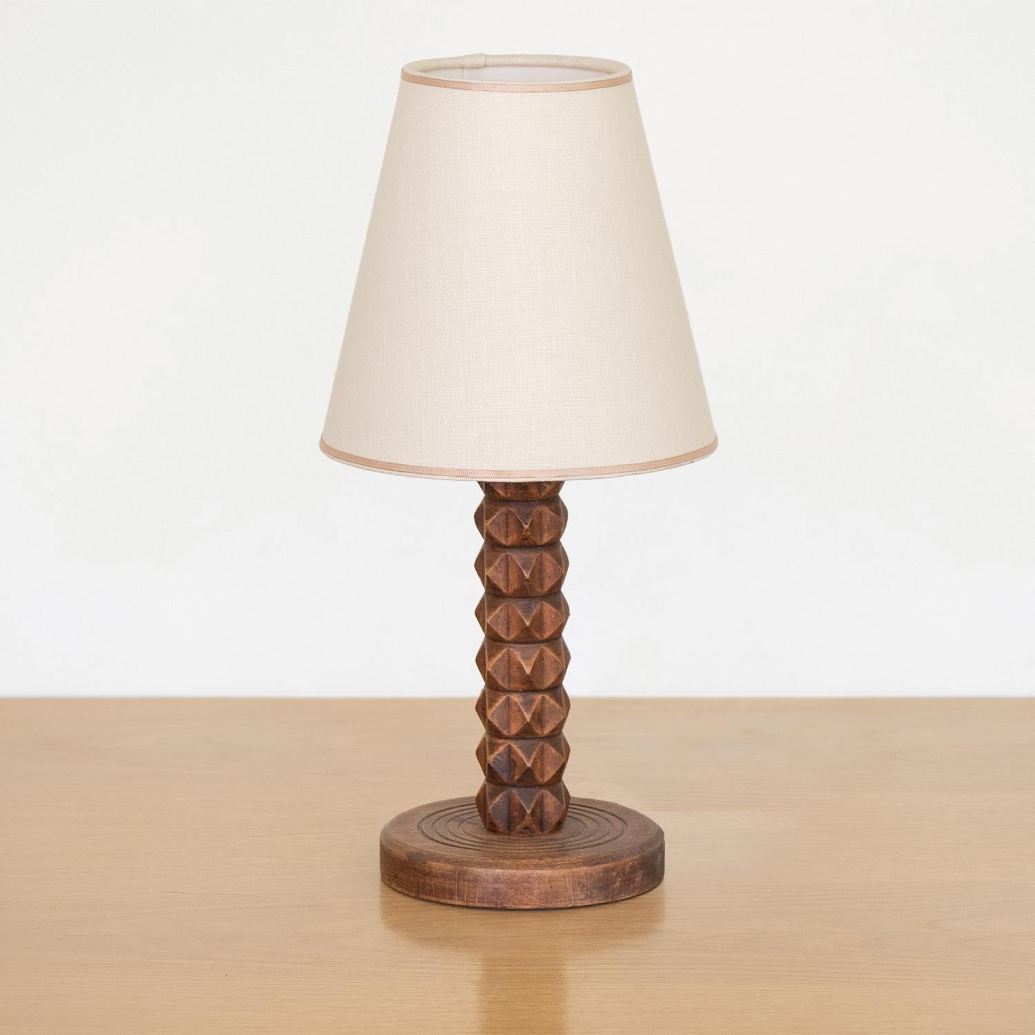 Small carved wood table lamp from France, 1940s. Beautiful carved chevron design with original dark wood finish. New linen shade with tan trim and newly re-wired.