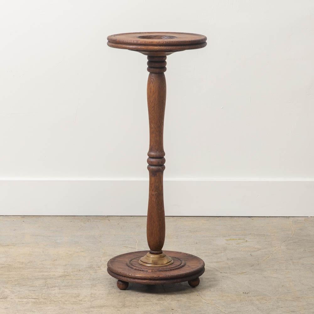 Preciosa mesa francesa de pedestal de madera tallada, con tablero circular y base que descansa sobre tres pequeños pies de bola. Vástago delgado de madera con detalle estriado y detalle metálico decorativo en la base. La parte superior circular