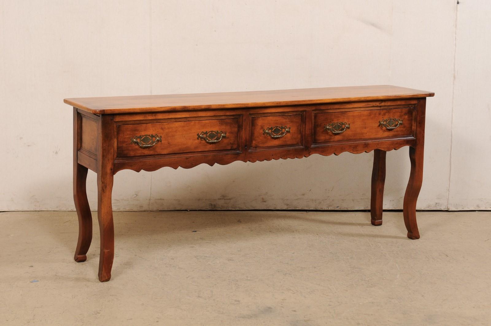 A French carved server console table with drawers from the mid 20th century. This vintage table from France features a rectangular-shaped top with rounded corners, atop a case which houses three drawers, set in horizontal fashion, along the front,