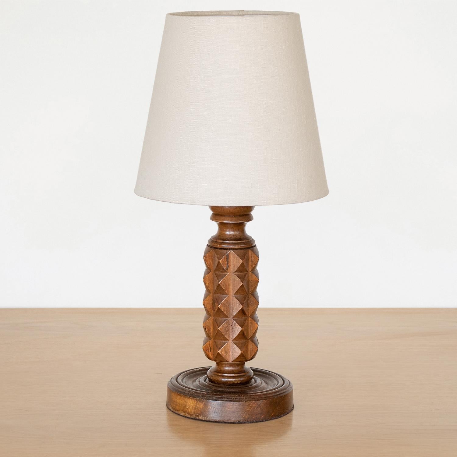 Carved wood table lamp from France, 1940s. Beautiful carved chevron design on stem with original dark wood finish. New ivory linen shade and newly re-wired. Takes one E12 base bulb, 40 W or higher using LED.