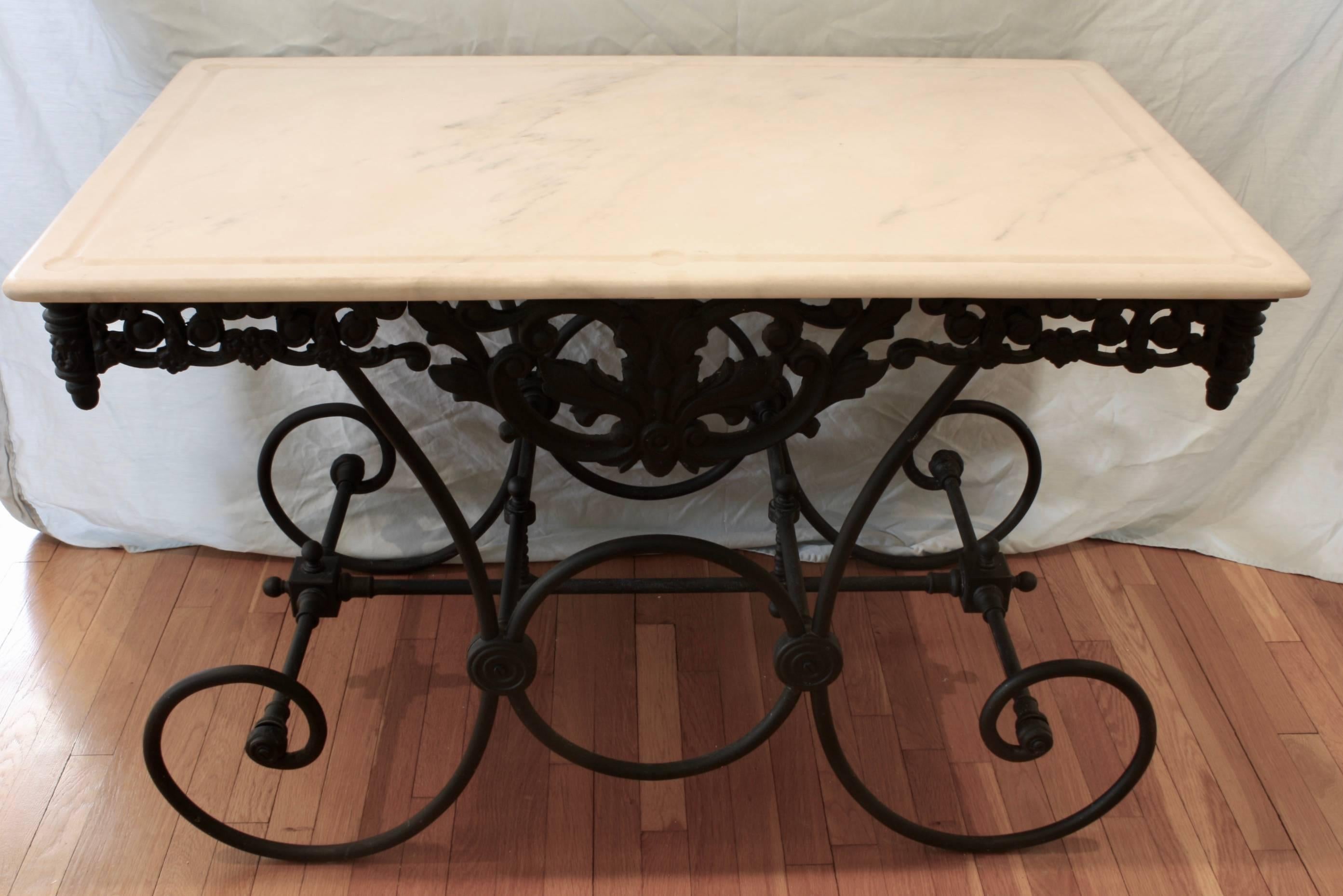 French cast iron and marble top Baker's table. The marble is white with some veining. The pierced cast iron apron features a stylized acanthus leaf in the front and back, and nice scrolling details around the perimeter, with finials in each corner.
