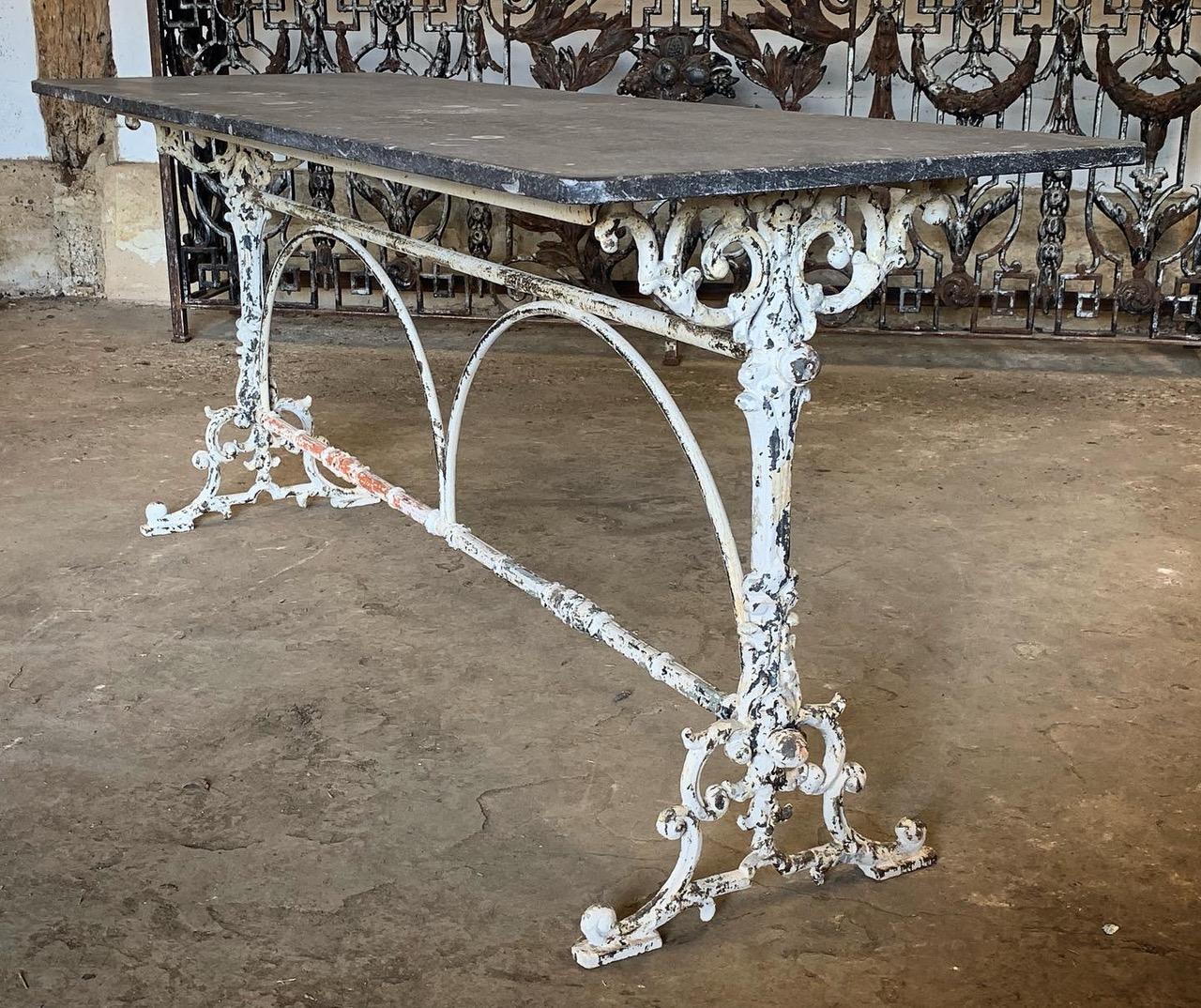 A beautiful early 20th century French bistro table with a cast iron base which has lovely original worn paint. The top is made from beautiful blue stone which has fossil like patterns in it. This table would make a wonderful garden table or would