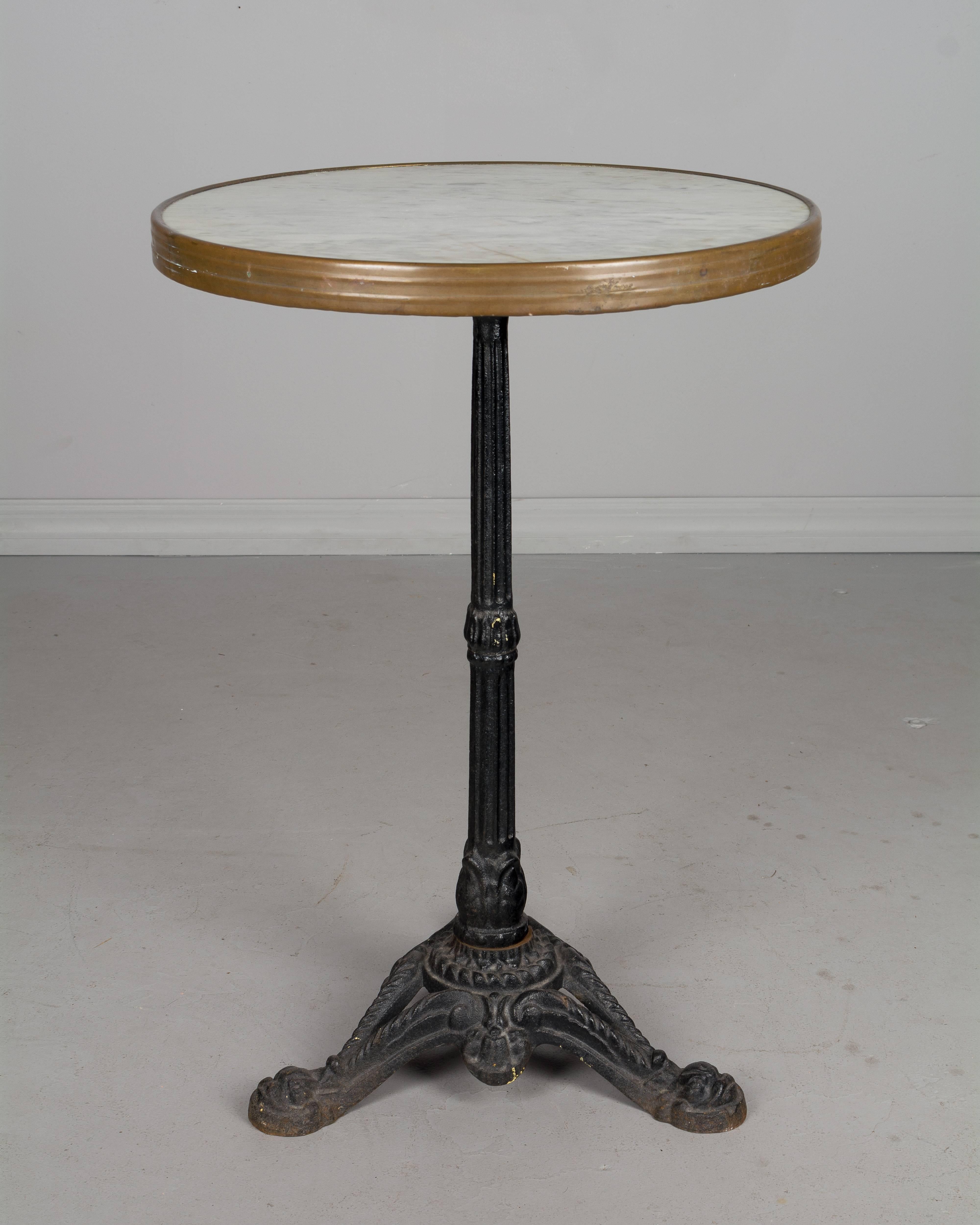 An early 20th century French cast iron bistro table. Original white marble top with brass surround. Very well made and in excellent condition. Please refer to photos for more details. We have a large selection of French antiques at Olivier Fleury,