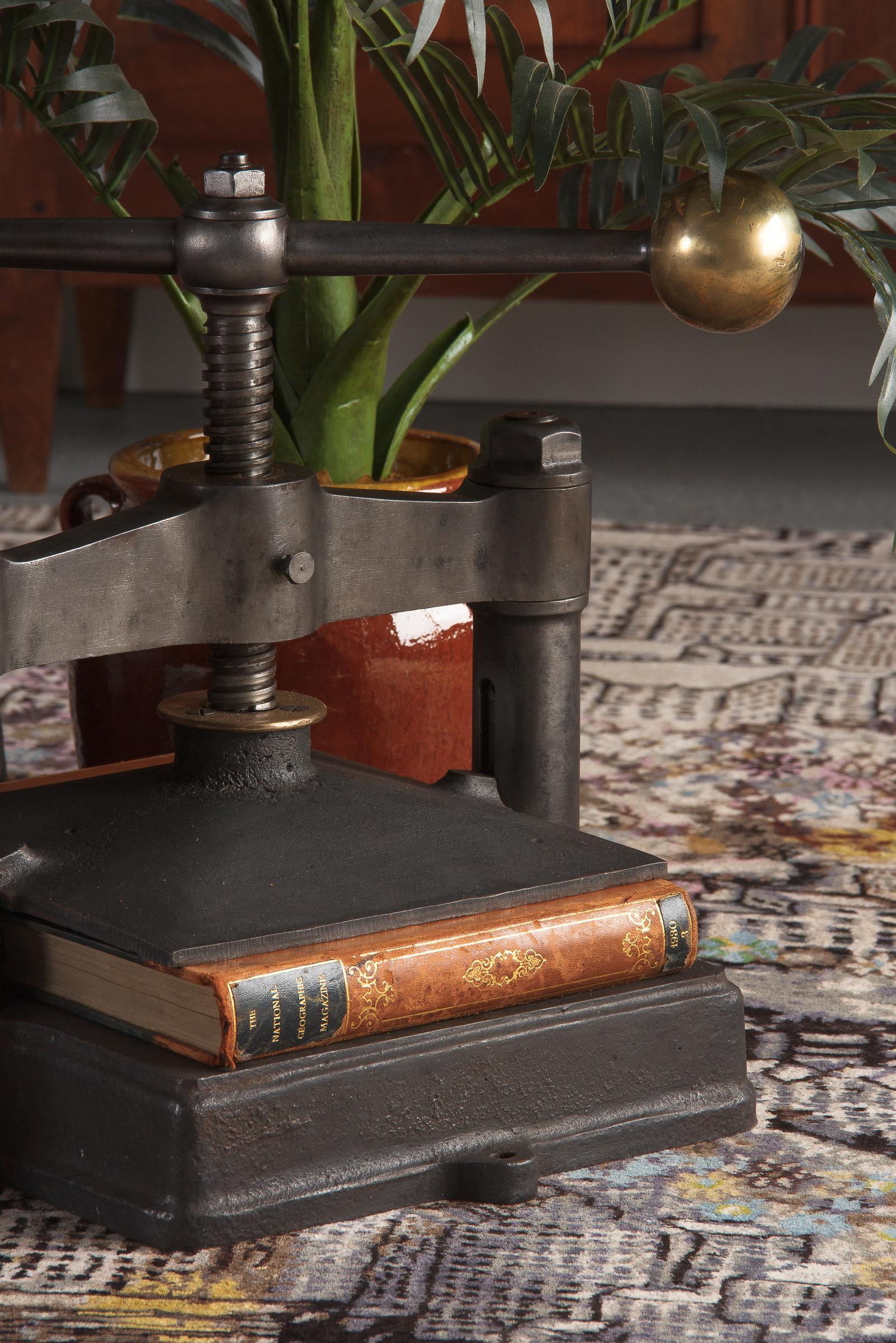 A large industrial antique cast iron and brass book press, French, circa 1900. Sturdy iron build with lightly molded square base, two stout posts joined by a thick lintel, and iron press plate connected to the manual screw controlled by wide