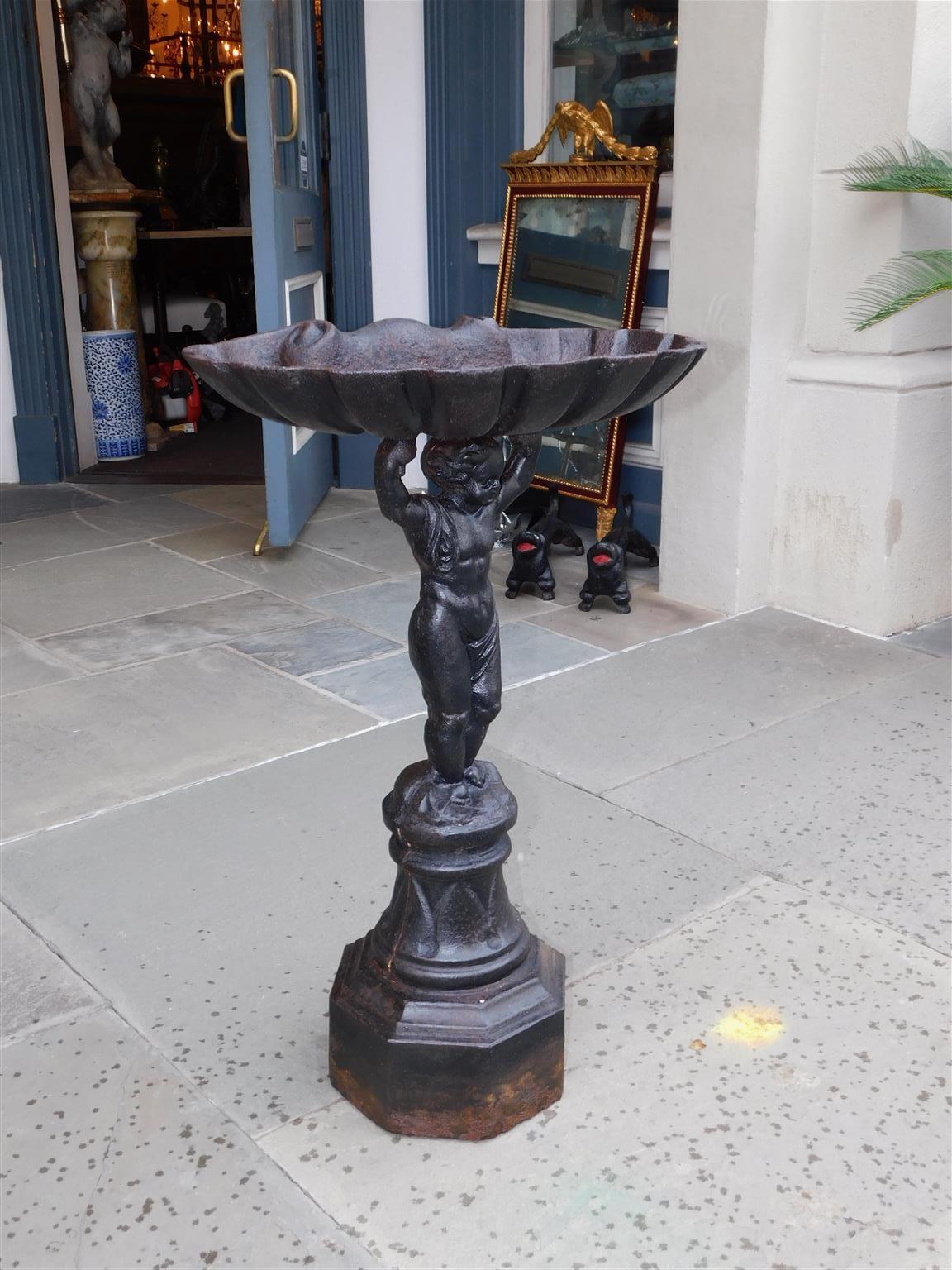 French cast iron figural putti shell bowl bird bath resting on a circular octagonal plinth. Late 19th century.