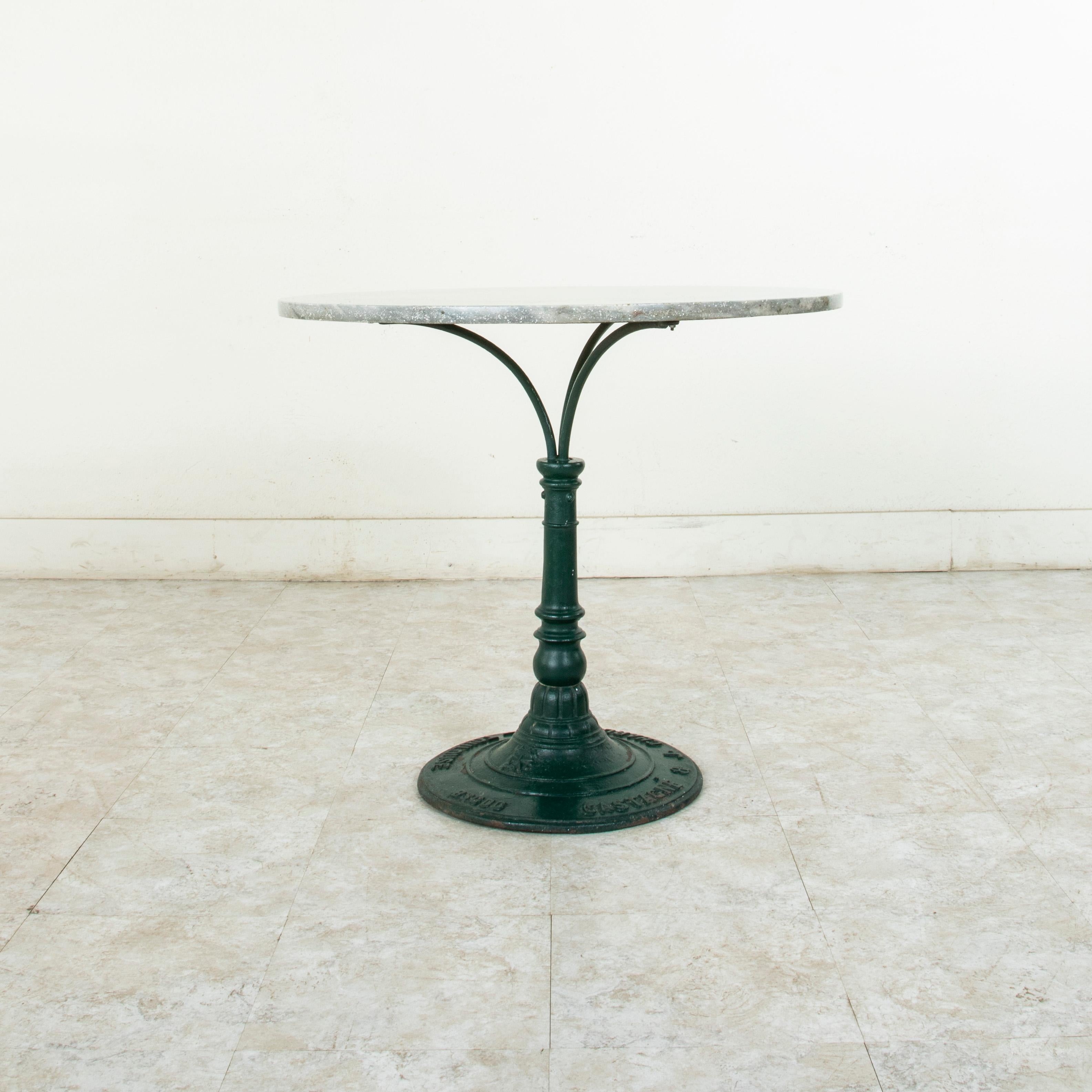 This French cast iron pedestal table or garden table from the turn of the 20th century features a handsome pale grey marble top with black and white veining. Its green painted cast iron footed base is marked by the maker Castagne &