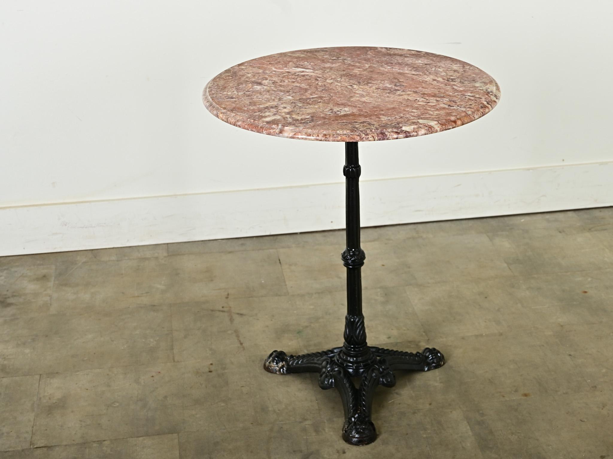 Late 19th century French cast iron round bistro table with beautiful red marble top. The circular piece of stone   exhibits swirls of earthy minerals in tones of jasper, pink, and sandstone–a charming spot for drinks or coffee in the kitchen and