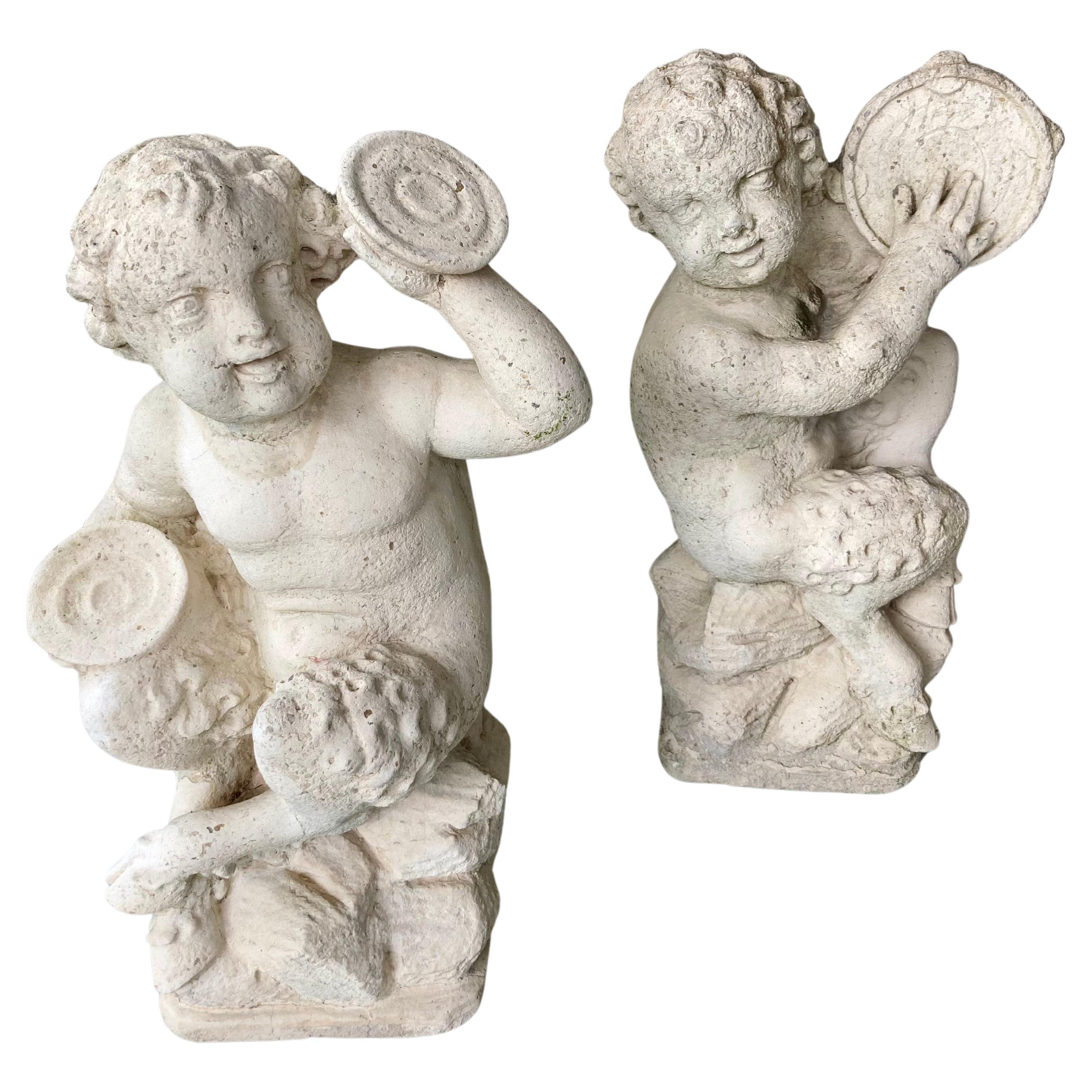 Paire de sculptures françaises en pierre moulée représentant des musiciens Pan et Putti