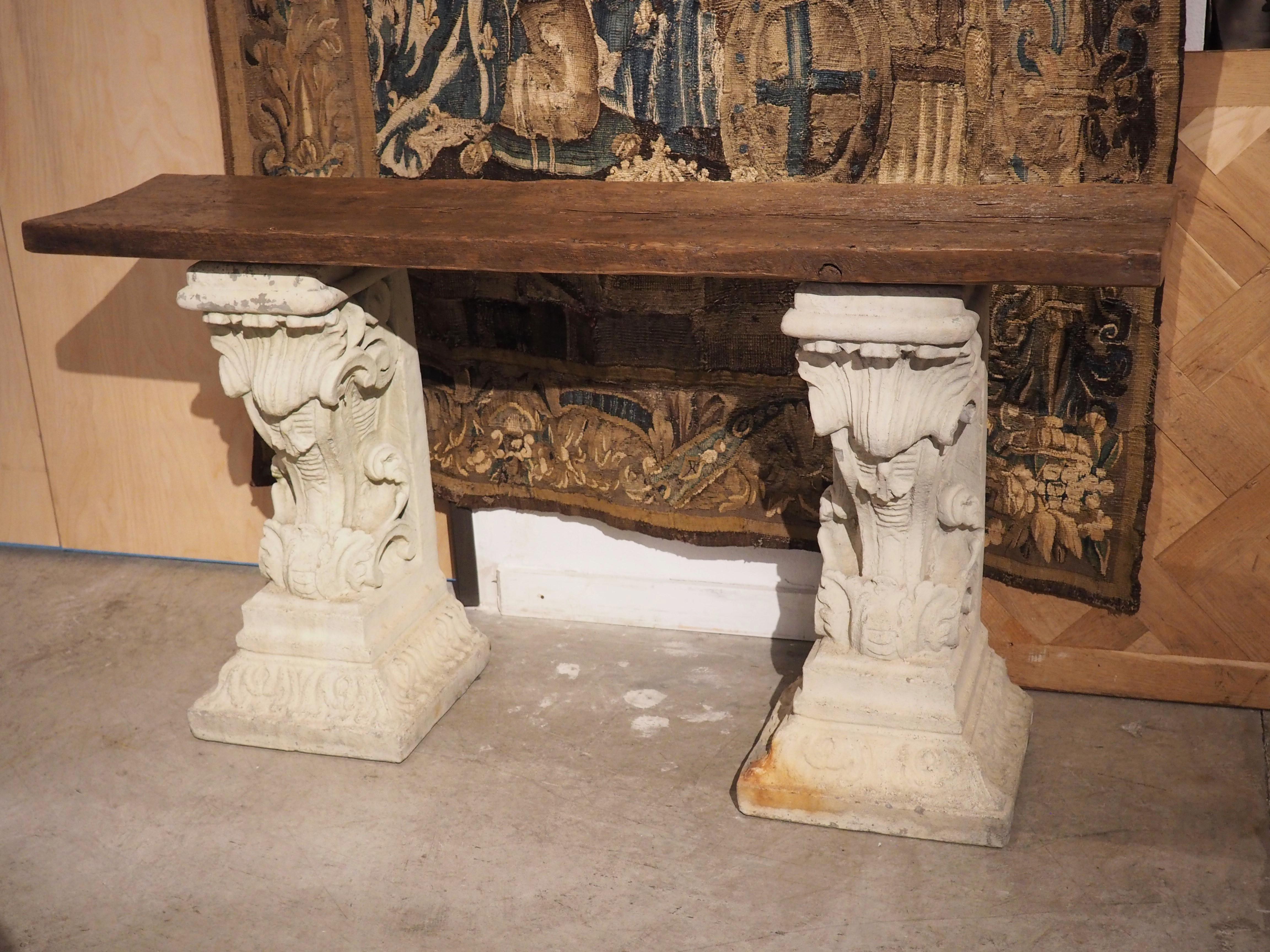 A pair of cement corbels cast in France in the 1900’s forms a highly decorative base for this console table with antique plank top. The two-inch-thick top is made of pine wood that was felled in the 1800’s, which explains the visible cupping that