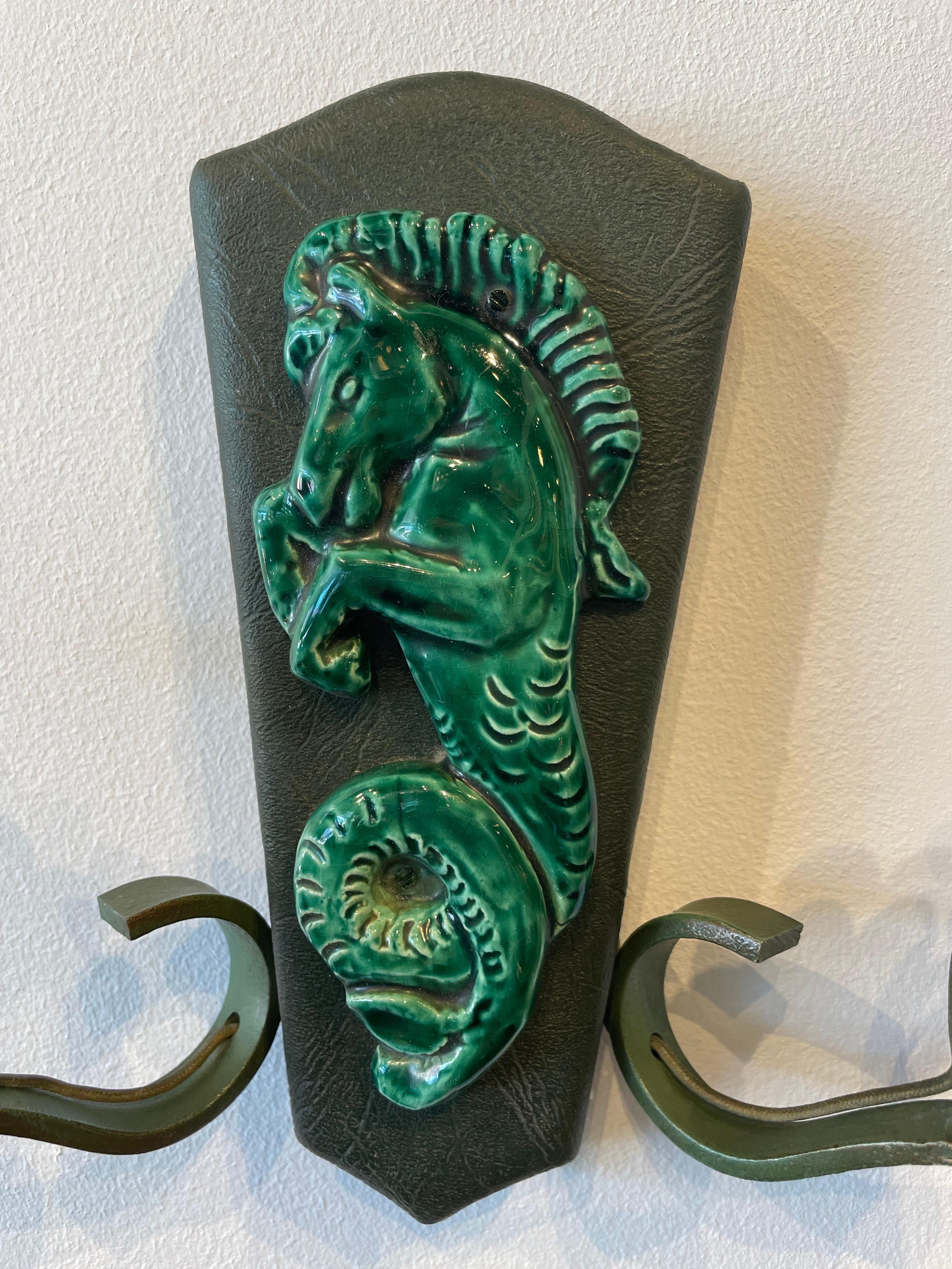 A rare set of 3 Deco wall sconces with double arm lights and themes of mermaid and seahorses. Metal work, leatherette and ceramic is very much in the style of Georges Jouve. Nice green emerald glaze, all original. May need to be rewired and we can