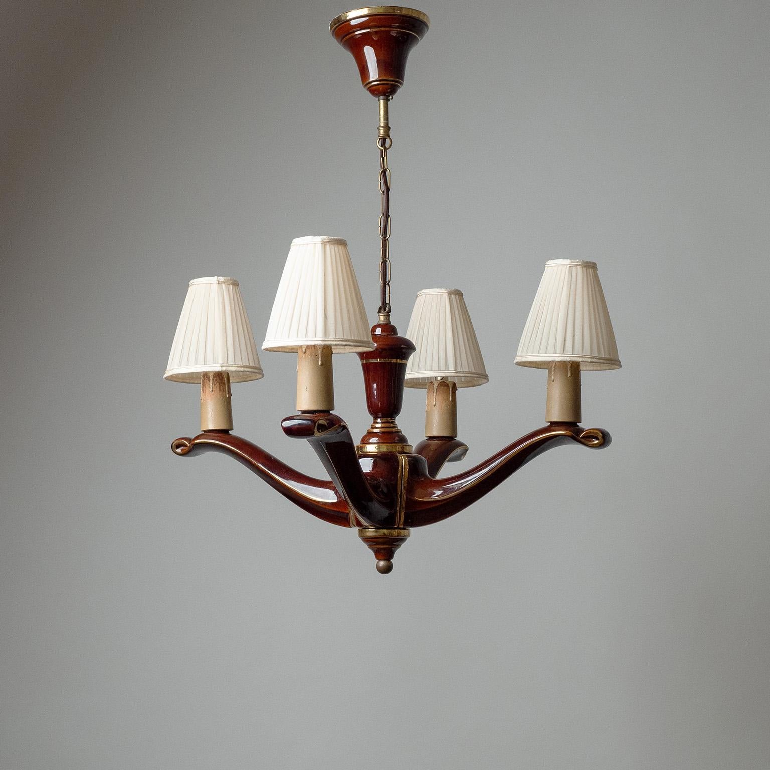 Fine French ceramic chandelier from the 1940s. Four-armed structure made of ceramic glazed in maroon with gold accent stripes. The original socket covers are made of painted wood. Four brass and ceramic E14 sockets with new wiring and shades.