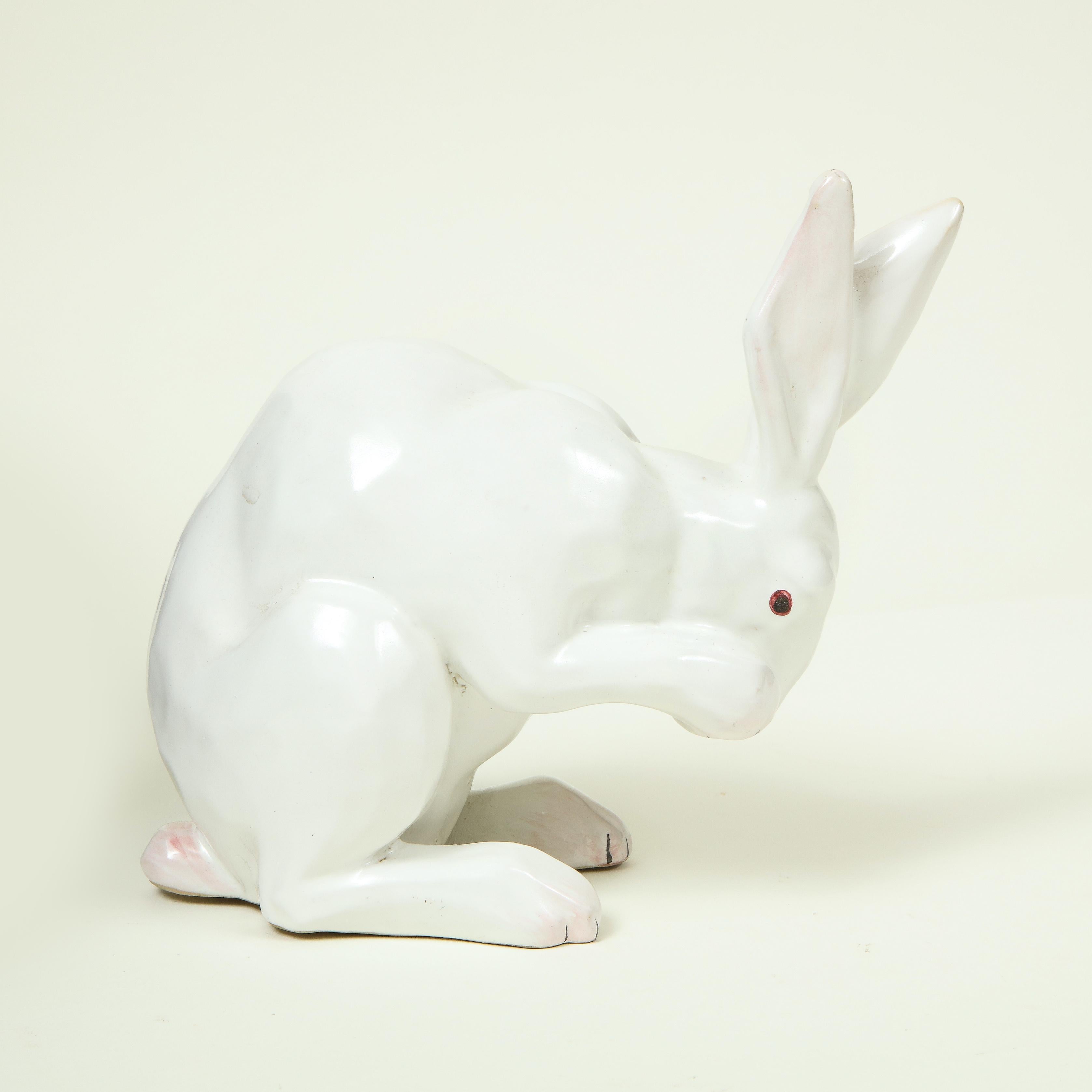 Figure of white crouching rabbit with amber eyes and upright ears. Underside marked 