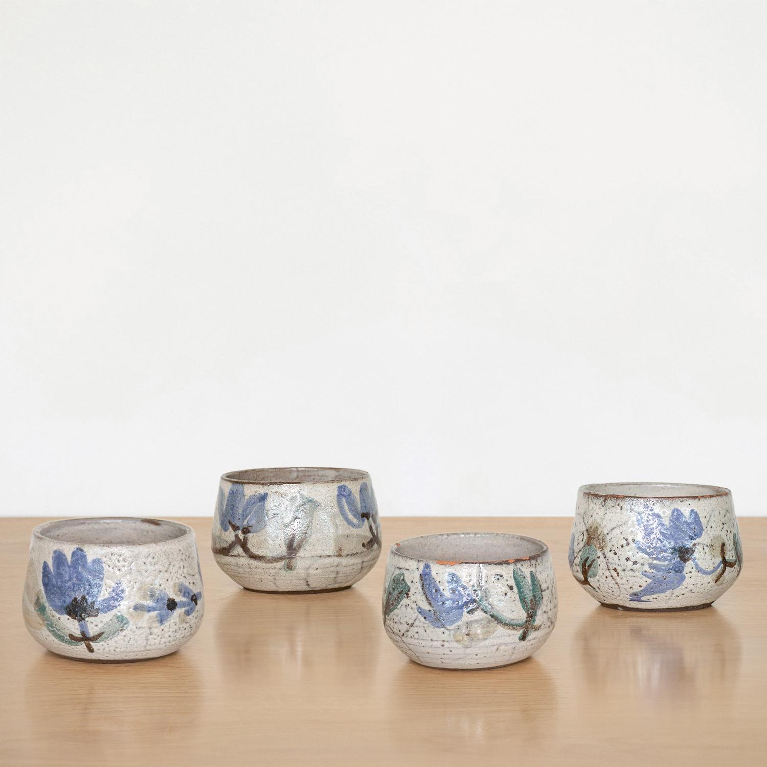Beautiful painted ceramic cup set from France, 1950s. Curved with hand painted flower motif in blue and grey coloring. Made by French ceramic artist Gustave Reynaud. Sold as a set of four.
