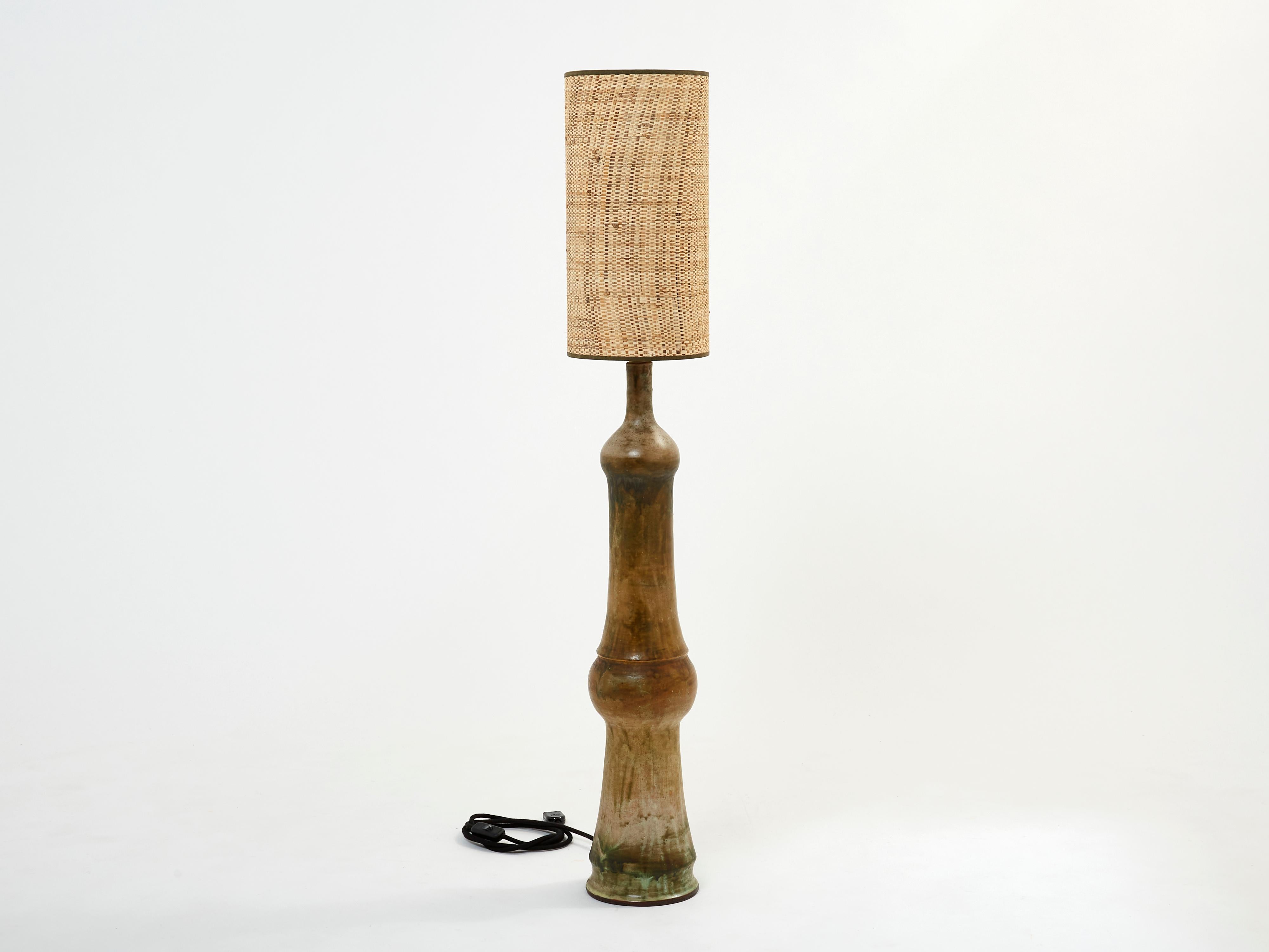 This is a beautiful and tall ceramic lamp signed P. This is an early 1960s work with beautiful contrast and presence. Matched here with a beautiful rattan shade with brown strapping, for a nice vintage look, this floor lamp will bring a very nice