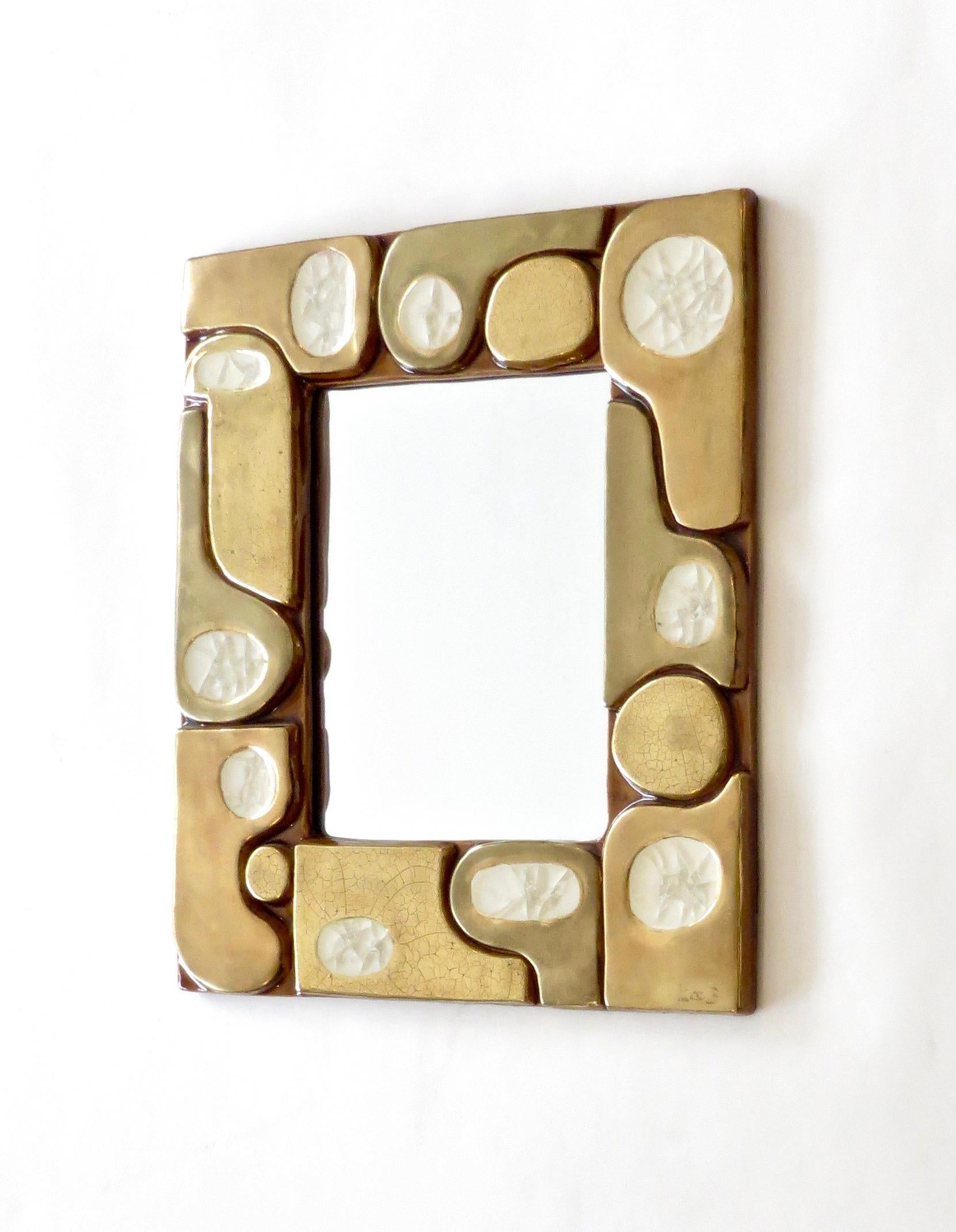 Un superbe miroir créé par Mithé Espelt, vers 1960, en France.
Le miroir est composé de morceaux de céramique émaillée craquelée dorée et d'inserts en verre fusionné cristallin.