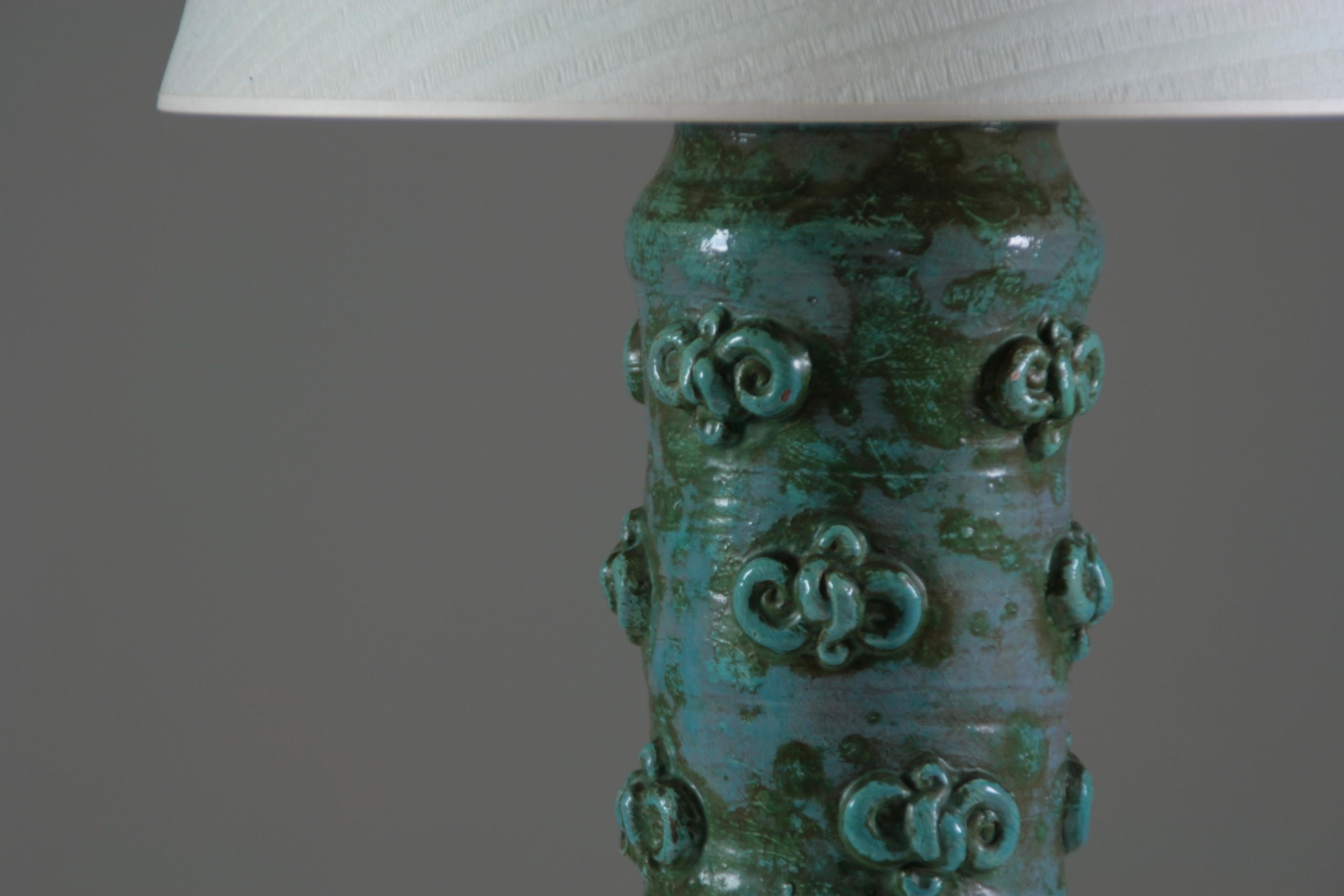 Lampe de table en poterie émaillée du céramiste français Jean Austruy, datant des années 1950. Belle décoration en relief sur l'ensemble des pieds. Belle condition vintage. Rares petits éclats visibles sur les photos. L'alimentation est entièrement