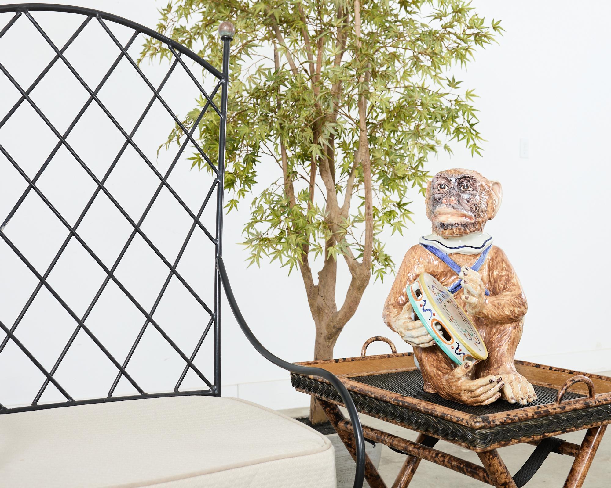 Skurrile französische Majolika-Keramikskulptur eines Tamburin spielenden Geldes, handbemalt. Die große Skulptur ist wunderschön detailliert mit hellen, lebendigen Farben in einer sitzenden Position abgebildet. Die Skulptur ist 18 Zoll hoch und hat