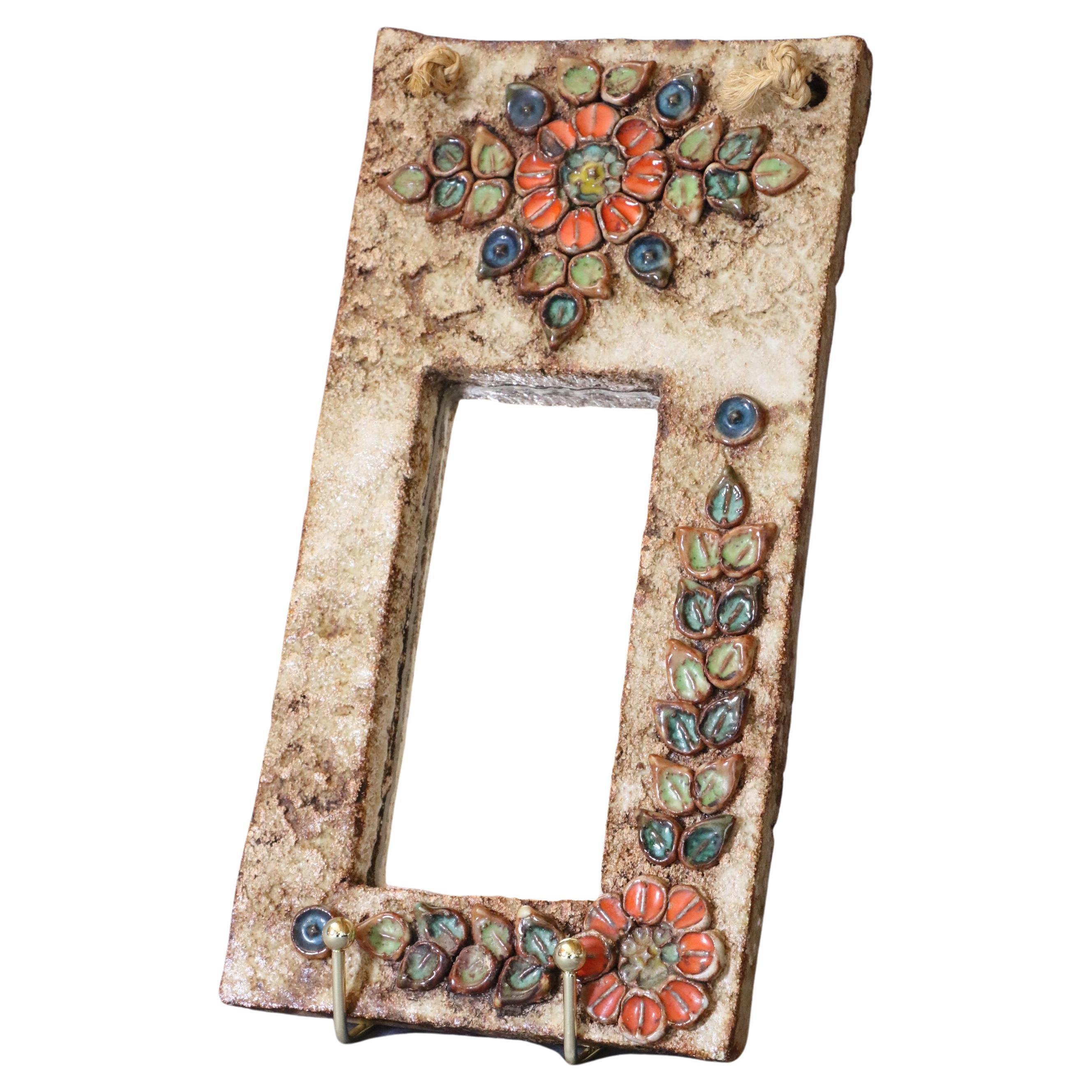 French hanging ceramic mirror - Vallauris, France - 1950s
Attributed to La Roue-Vallauris. 

Ochre coloured glazed ceramic mirror decorated on the frame with coloured flowers. This pretty mirror, typical of Vallauris mid-century creations, combines