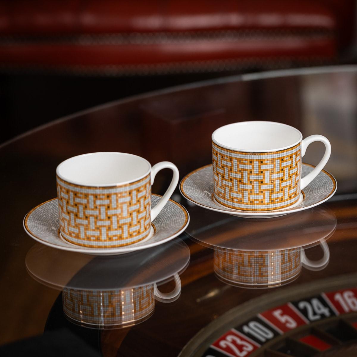 Hermès, Mosaique au 24 or paire de tasses à thé et soucoupes en porcelaine.
Les mosaïques décoratives sont sérigraphiées et minutieusement appliquées à la main à l'aide de carreaux d'or 24 carats. Avec ses motifs géométriques, la collection Mosaïque