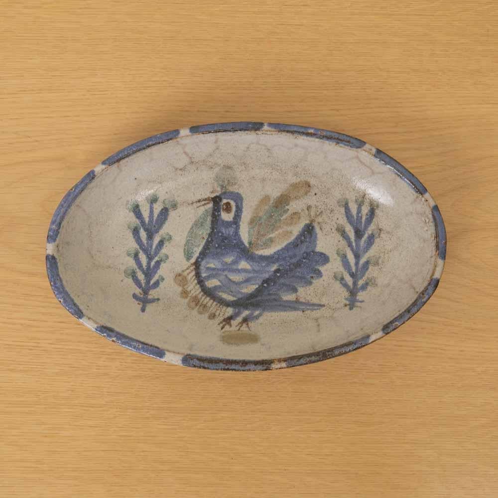Precioso plato ovalado de cerámica del artista francés Gustave Reynaud de la década de 1960. Esmalte blanquecino con motivos de pájaros pintados en azul y verde apagado. Firmado en la parte inferior. Estupendo como colgador o para colgar en la pared