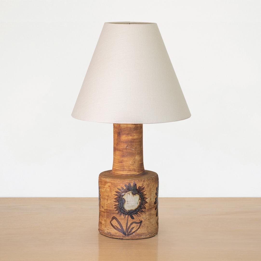 Beautiful French ceramic table lamp from France, 1960's. Round ceramic two tier base in dark brown painted colors with hand painted flower motifs. New tapered linen shade and newly re-wired. 

 
 