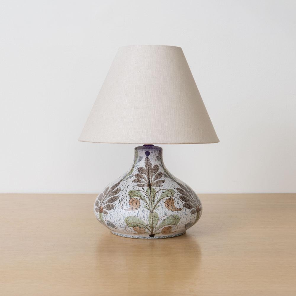 Lovely ceramic painted bulbous lamp from France, 1960s. Matte glazed ceramic base in light blue tones with beautiful floral motifs. Newly rewired with new tapered linen shade. Takes one E12 base bulb, 40W or higher using LED. 