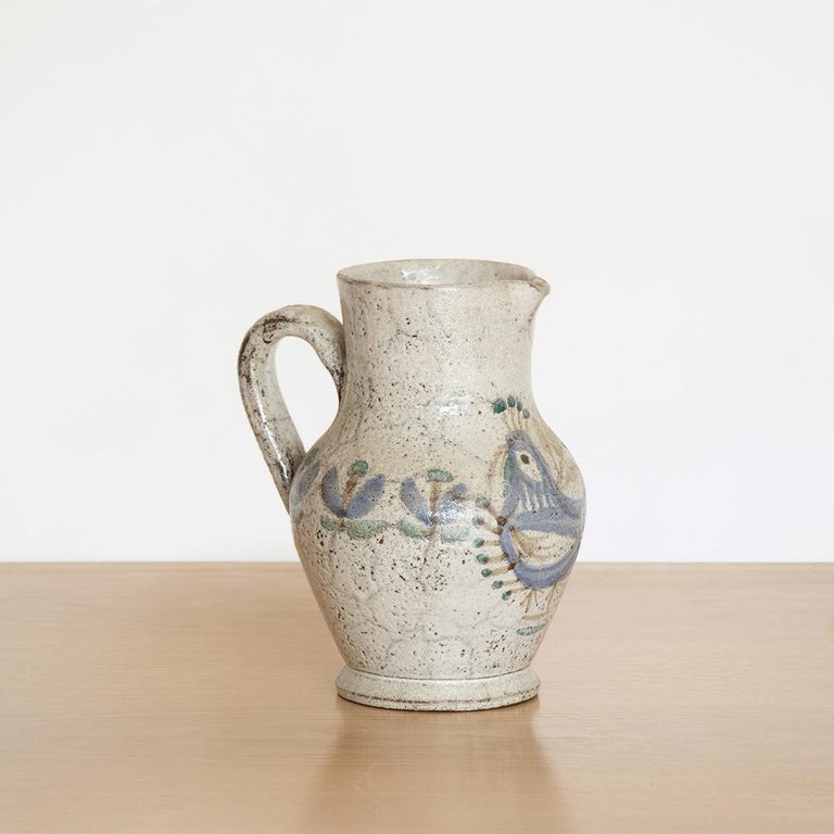 Beautiful painted ceramic pitcher from France, 1950's. Curved handle with painted flowers and bird motif in blue grey coloring.
   