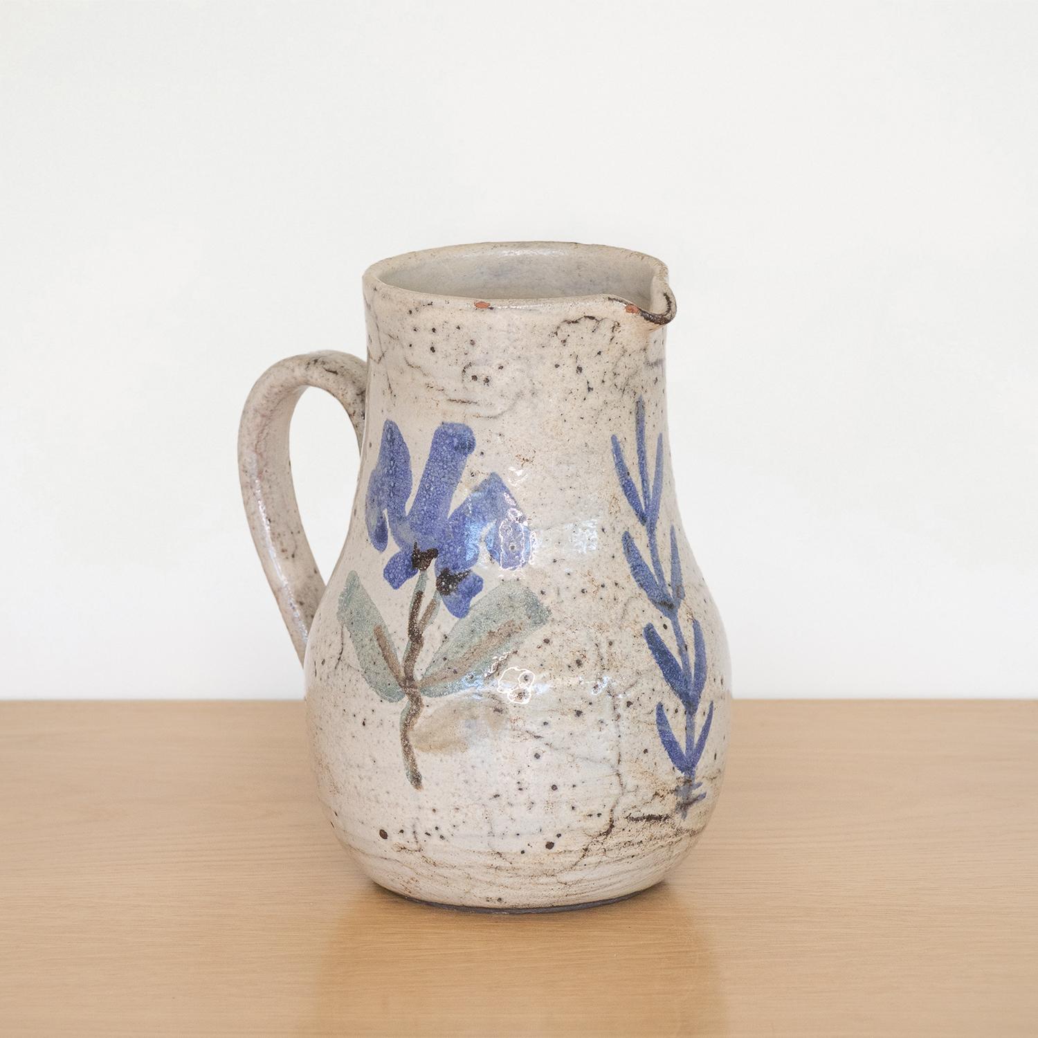 Beautiful painted ceramic pitcher from France, 1950s. Curved handle and spout with hand painted flower motif in blue and grey coloring. Made by French ceramic artist Gustave Reynaud.