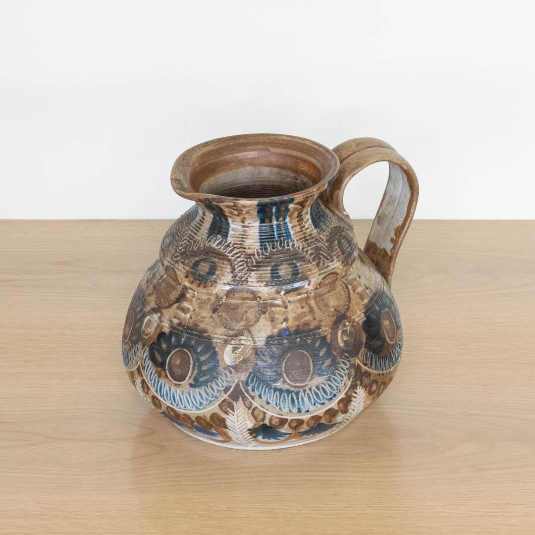 Incredible large ceramic pitcher made by French artist Jean-Claude Courjault, 1960's. Beautiful brown and blue painted floral motif with etched detailing. Great vintage condition and signed on underside. Beautiful decorative piece. 