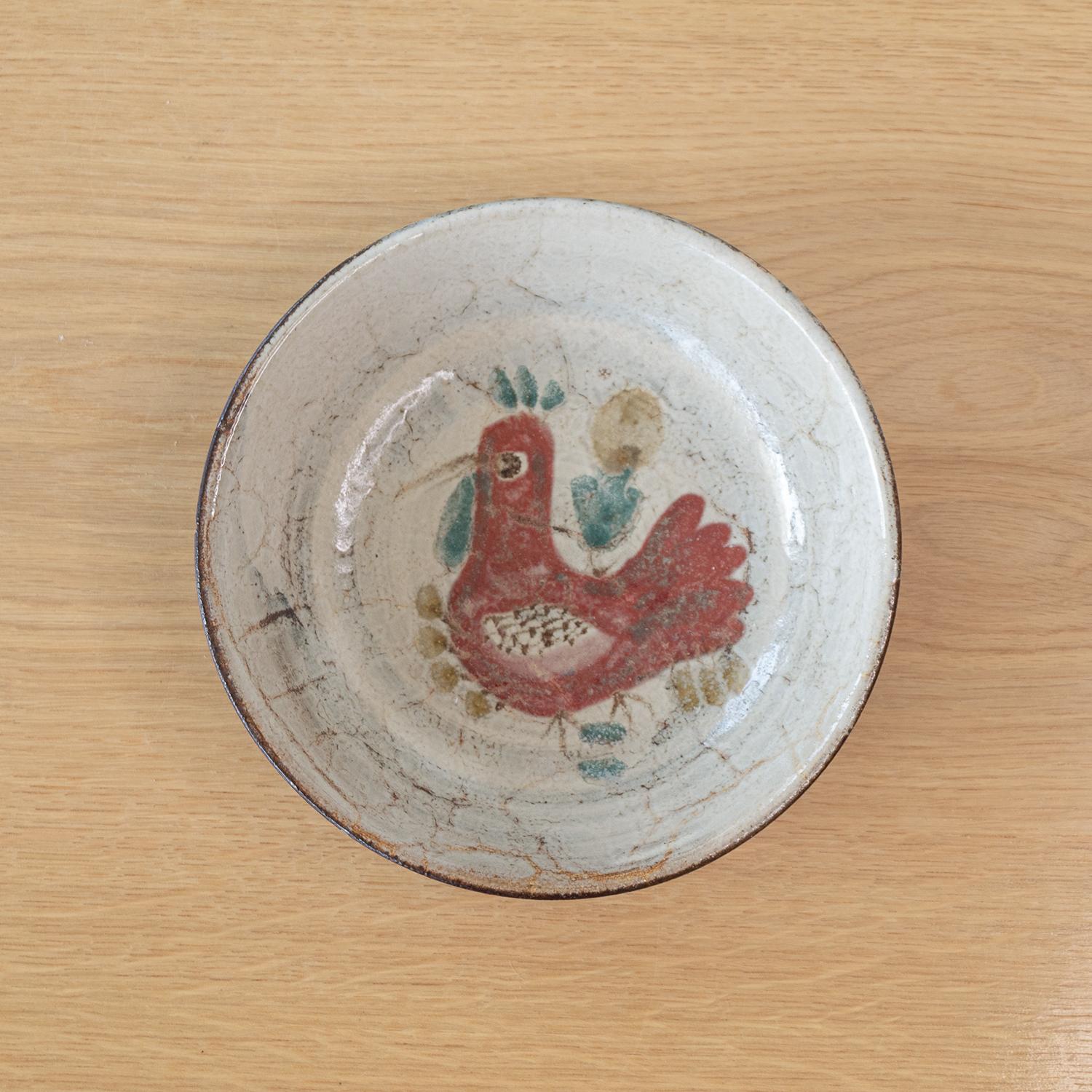 Beautiful ceramic plate by French artist Gustave Reynaud from the 1960s. Deep plate with off-white glaze with maroon and muted green painted rooster motif. Signed on bottom. Great as catch-all or to be hung on the wall as art.
 