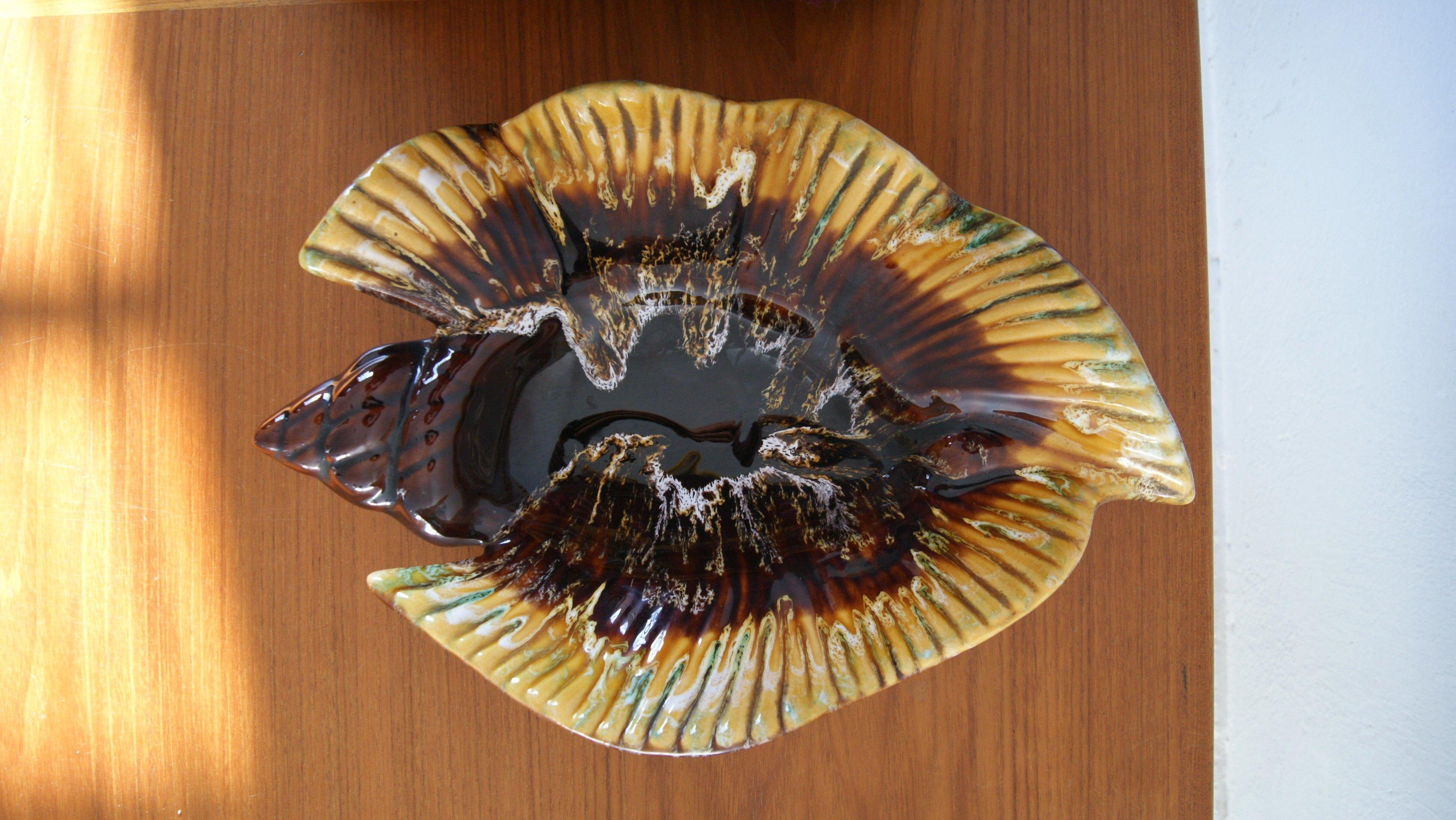 Una ciotola decorativa a forma di conchiglia, prodotta nei leggendari laboratori di Vallauris - il centro francese della ceramica artistica, che a metà del XX secolo attirò artisti come Picasso e Roger Capron.

Questo pezzo delizia con la sua forma