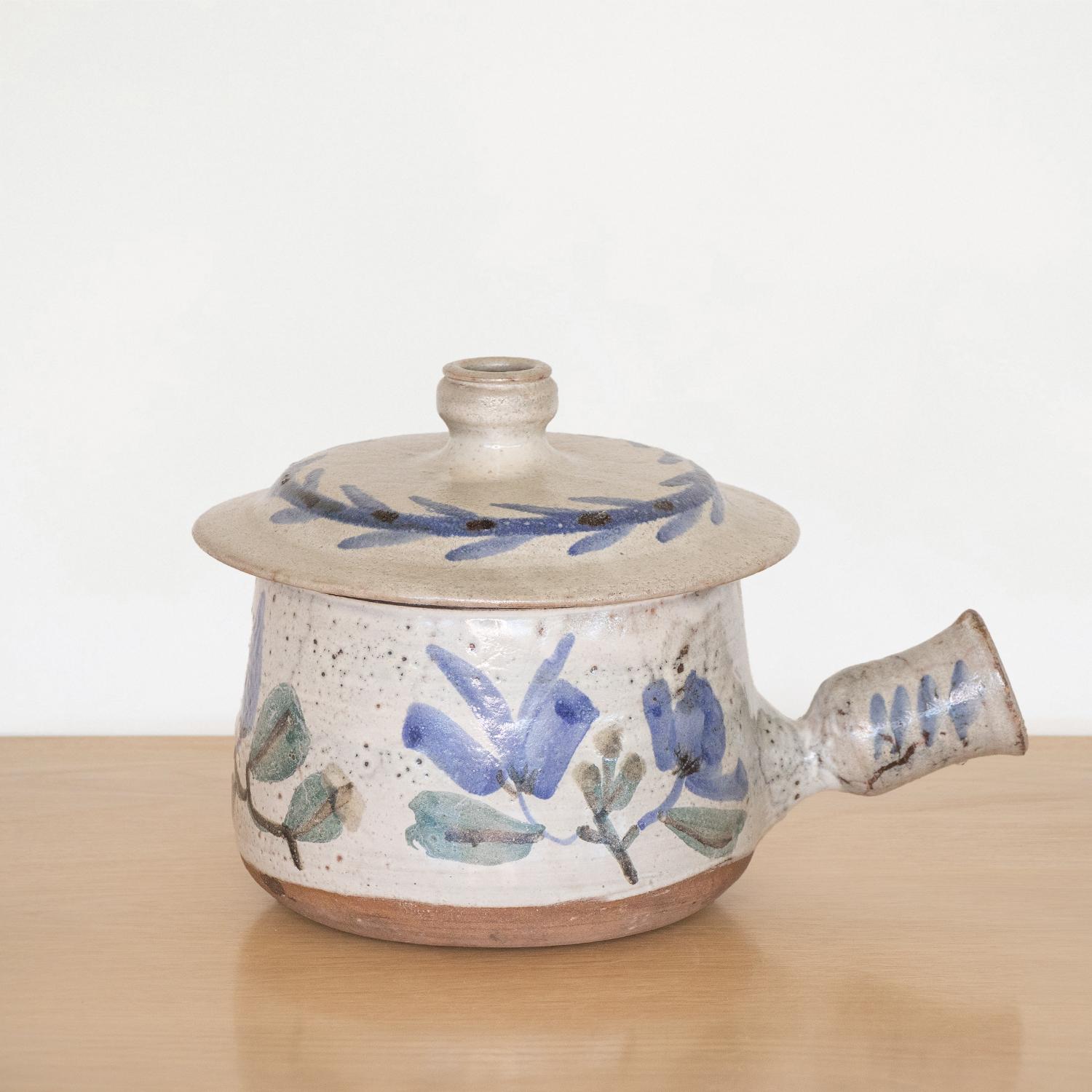 Beautiful hand painted pot with lid by Gustave Reynaud from France. White-grey glaze with blue and green painted floral motif. Handle and removable lid. Stunning display piece. Signed.