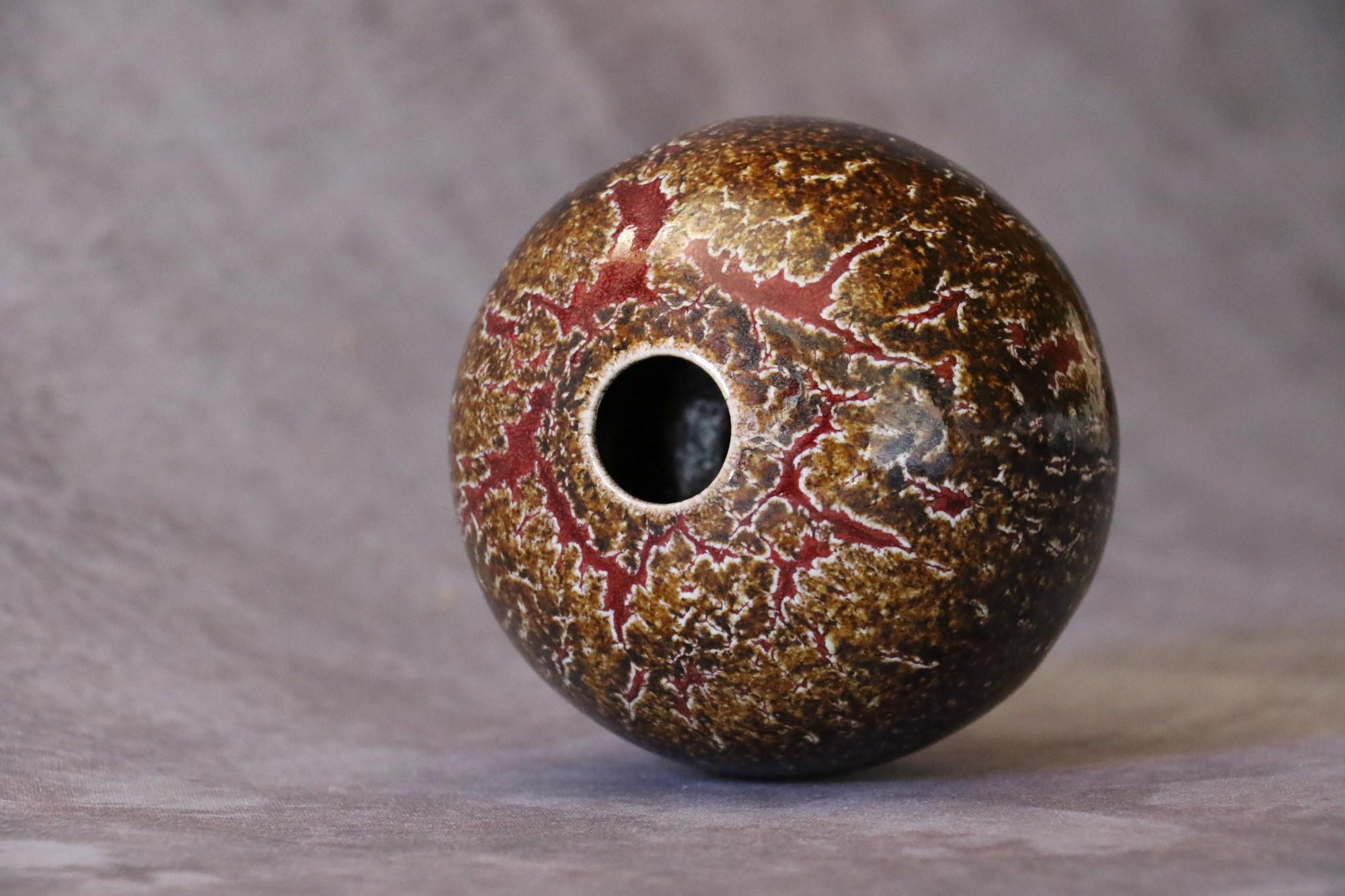 French ceramic ball vase by Marc Uzan - circa 2000
Delicate enamelling in red and brown tones - Ring neck
Signed under the base
Very good condition

--------------------------
Born in Sousse, Tunisia in 1955, Marc Uzan discovered modelling at