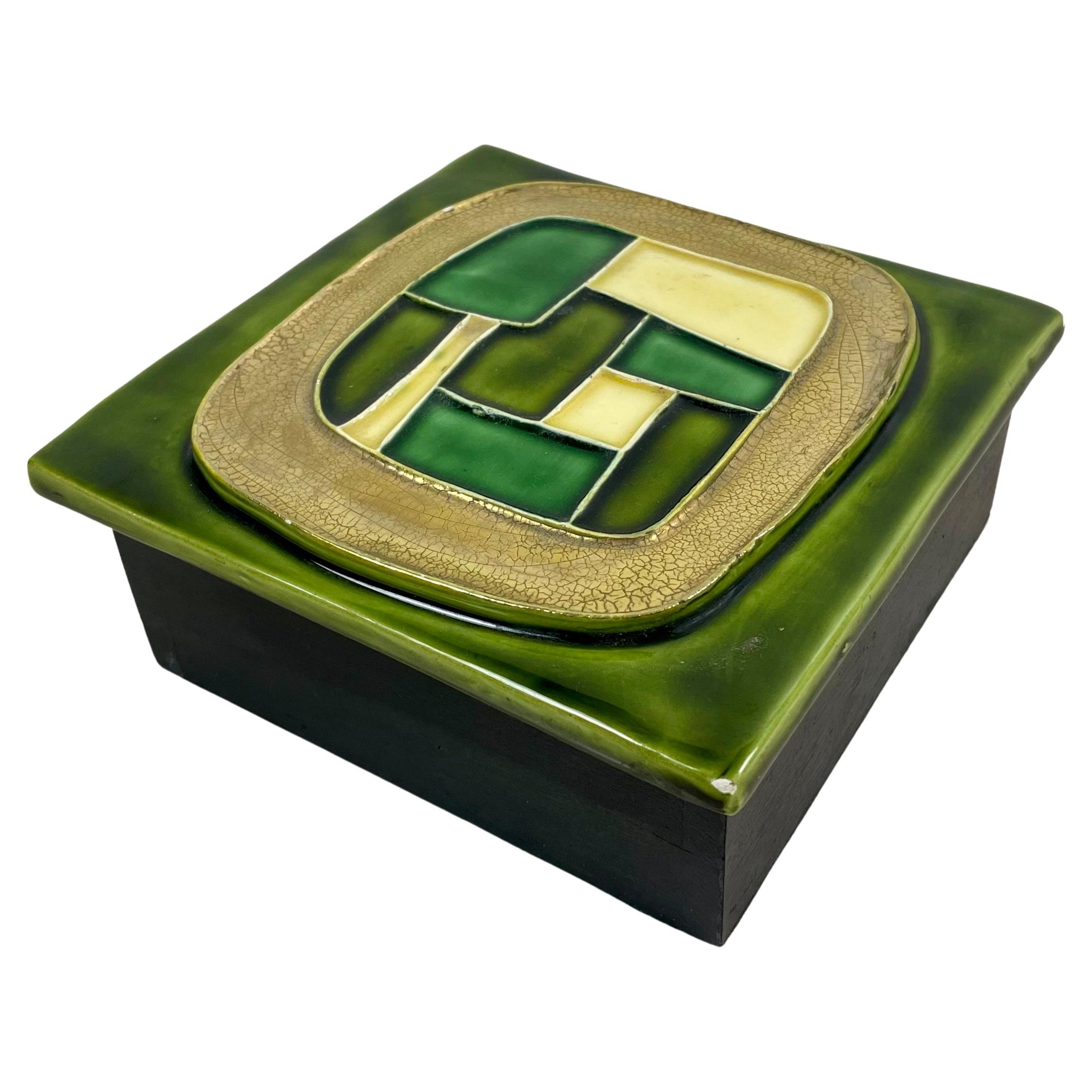 Boîte à secrets, boîte à bijoux, boîte de rangement, rangement rectangulaire avec couvercle en céramique émaillée dans les tons de vert et base en bois, par Mithé Espelt.
La boîte est décorée de formes géométriques. Cette boîte donne un résultat