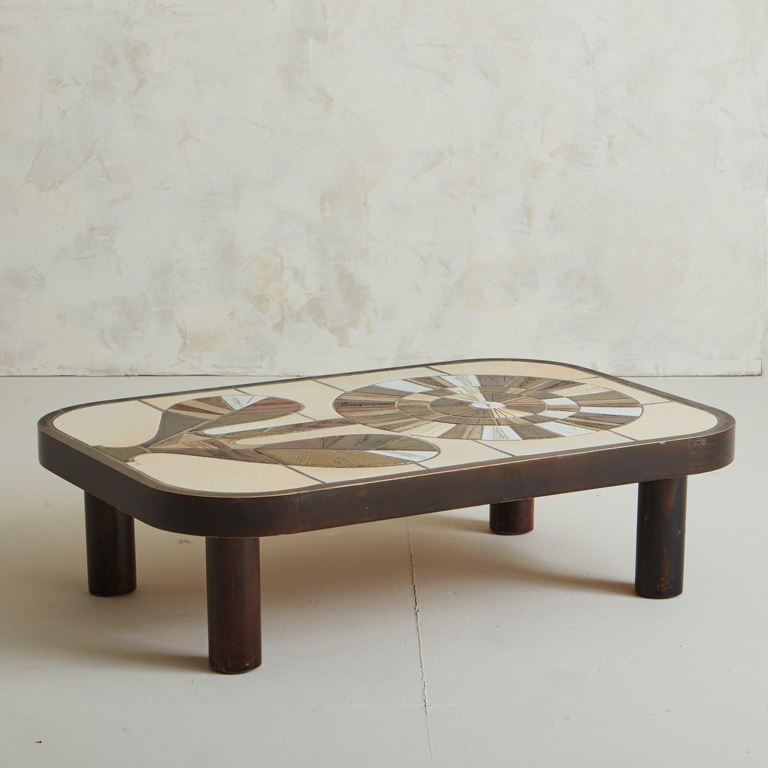 A 1960s coffee table by Roger Capron featuring ceramic tiles from Vallauris, France in a flower motif design. The rich variations in color on these tiles is astounding and contrast beautifully with the dark wood frame. Incised stamp, ‘Capron