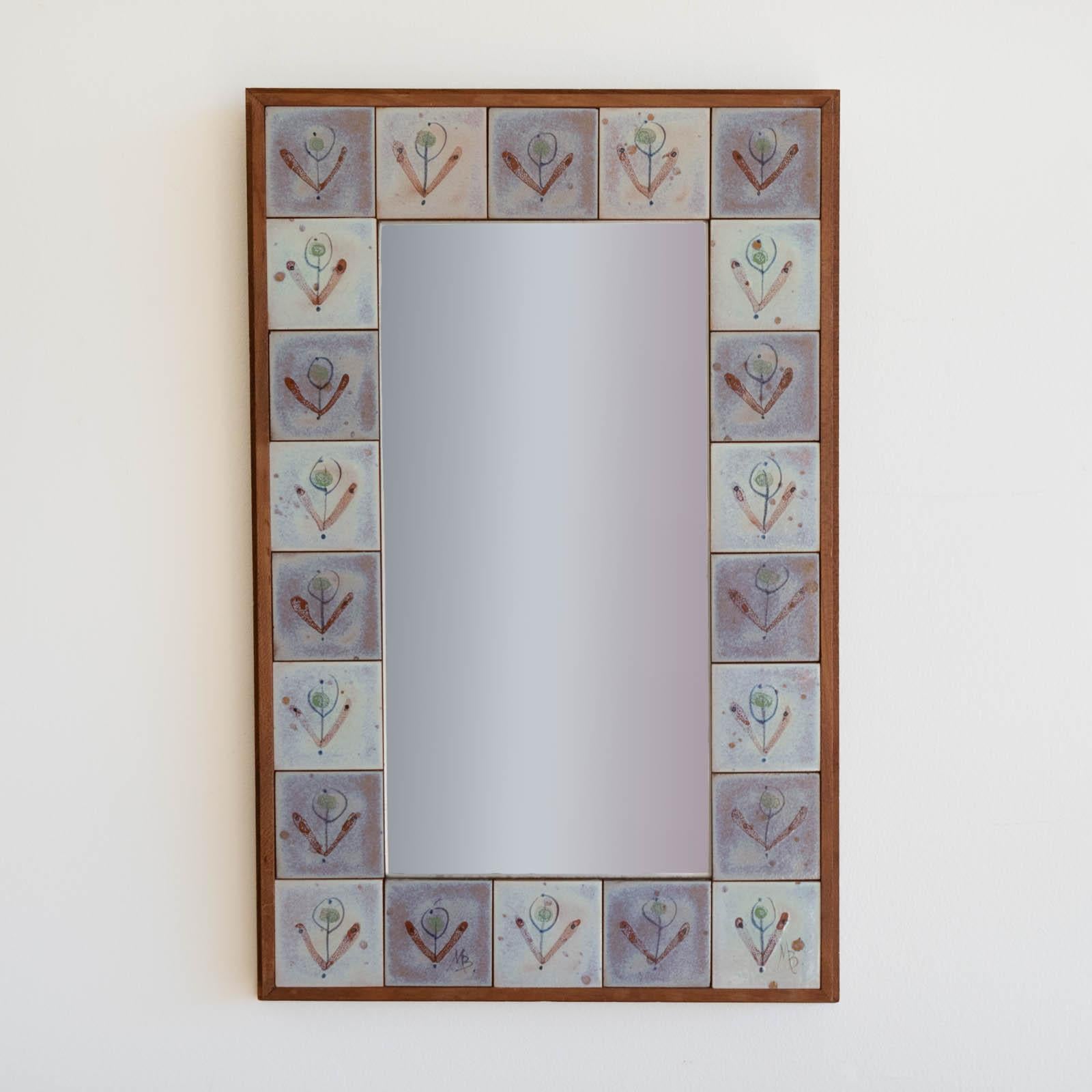 Lovely ceramic tile and wood mirror from France, 1950s. Wood frame with blue and purple ceramic tiles with plant motif detail. Original mirror and wood finish show great age and patina. 