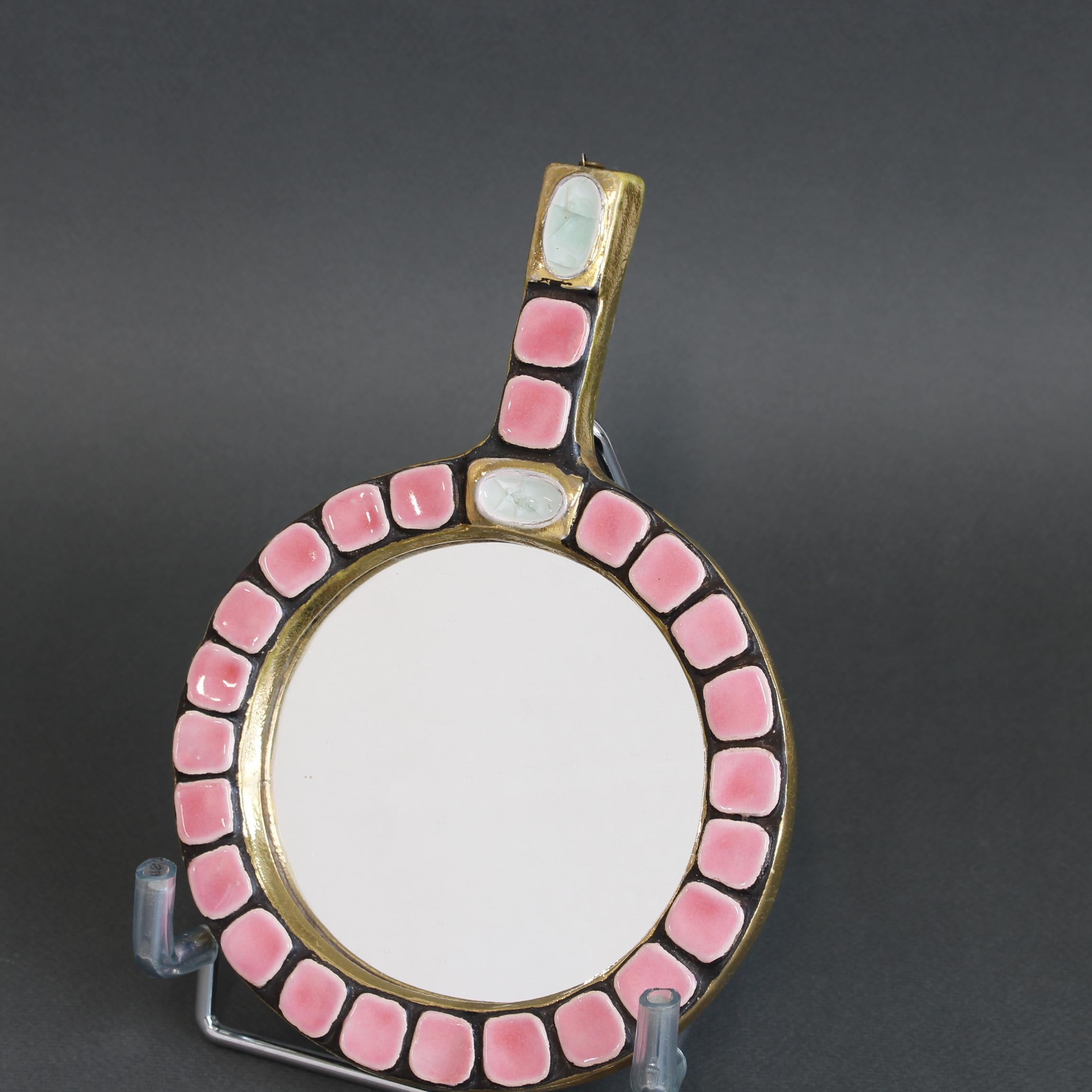Ceramic tiled circular hand mirror by Mithé Espelt (circa 1970s). An elegant piece of decorative art on a glazed golden craqueleur ceramic frame with surrounding pink glazed tiles. A faintly pastoral green enamel stone with gold surround sits in the