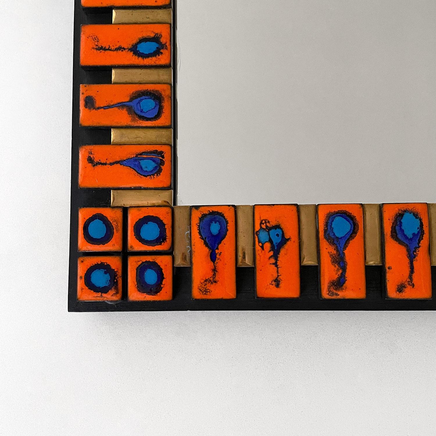 French ceramic tiled mirror in the style of François Lembo
France, circa 1960s
Bold statement mirror comprised of handmade ceramic tiles
Vibrant orange perfectly contrasts the deep ocean blue accents
Matte gold interior lines the black iron