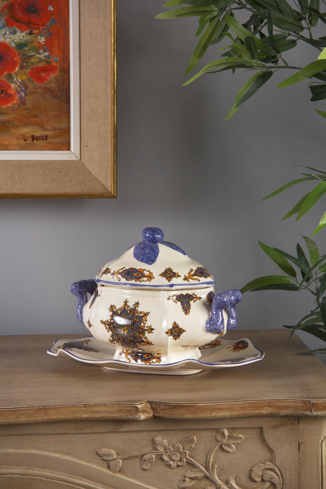 A charming glazed ceramic lidded tureen and underplate with hand painted decorative glazing, French, circa 1950. Scalloped edge underplate supports a wide, lobed bodied double handled tureen with a scalloped edge lid. All pieces feature elaborate