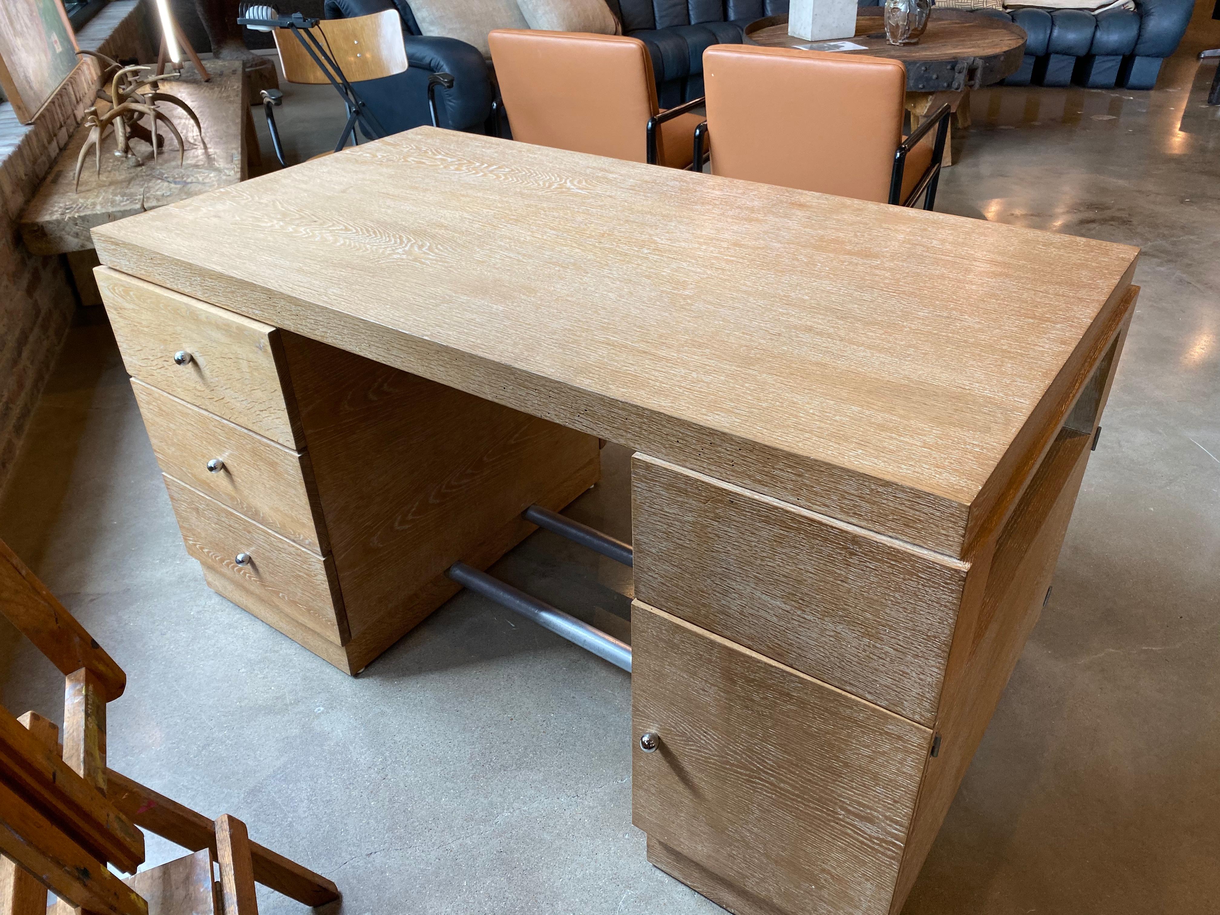 Partners desk of French white oak with cerused finish. Cabinetry on both sides with ample storage, it can be floated in a room. Plated metal rods create foot rests at base. Well constructed and heavy. Late Art Deco or early Mid-Century Modern
