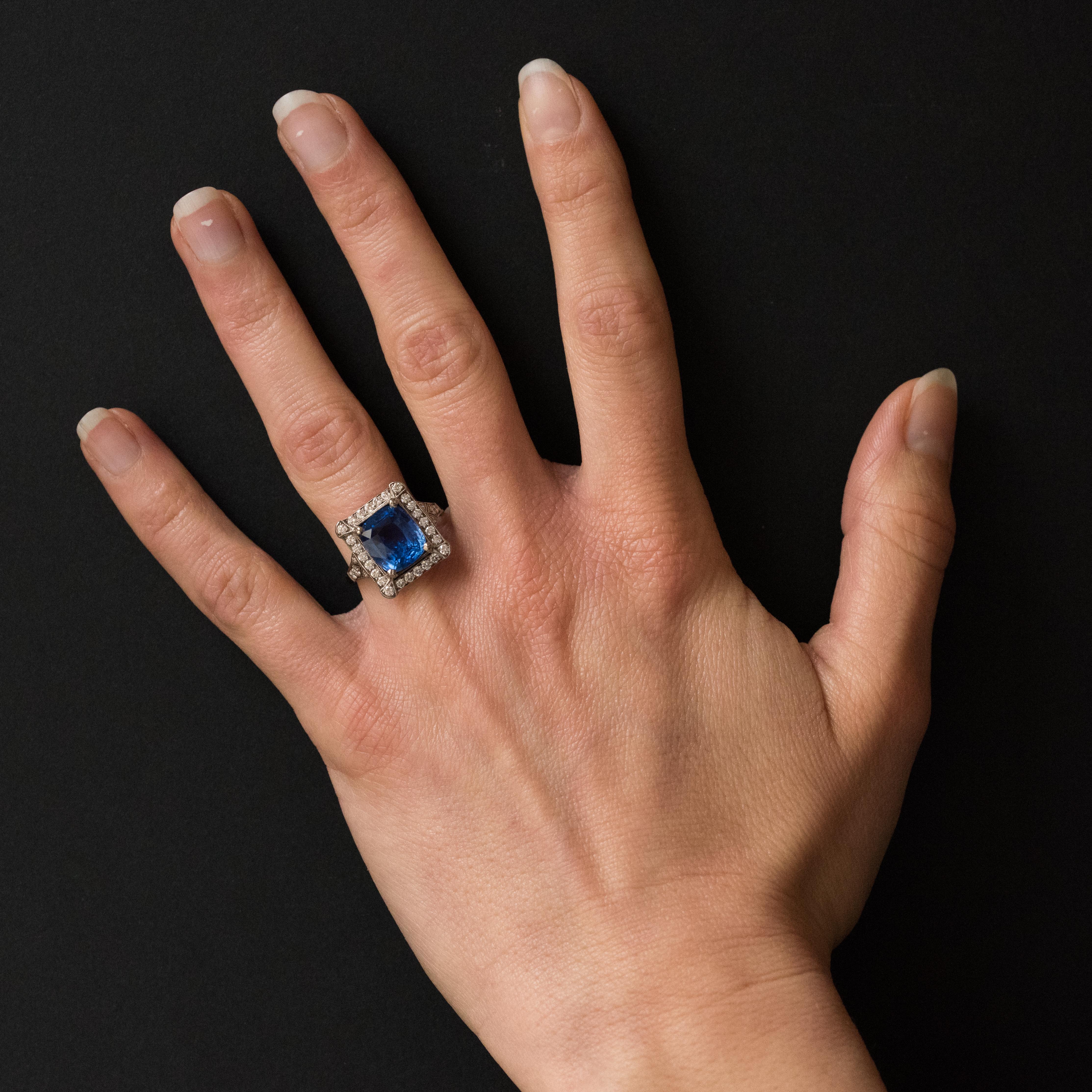 18K white gold ring, eagle's head hallmark.
This splendid rectangular shaped sapphire and white gold ring boasts a cushion cut Ceylan Blue sapphire held by 4 claws surrounded by brilliant cut diamonds of which the 4 corner ones are surmounted by a