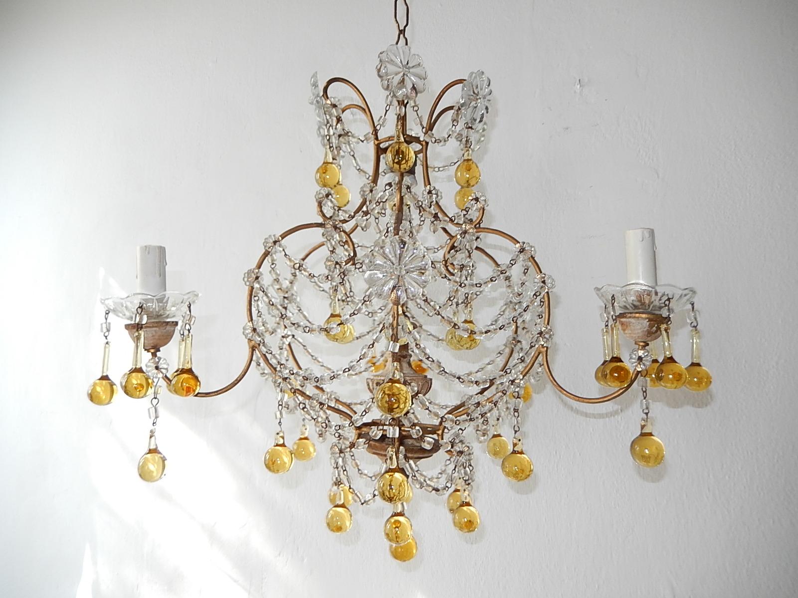 Housing four lights total. One light in centre top. The three encircling sit on wood posts and crystal bobeches dripping with champagne color Murano drops.  Gilt metal with glass florets and macaroni beading swags. Many champagne bulbous Murano